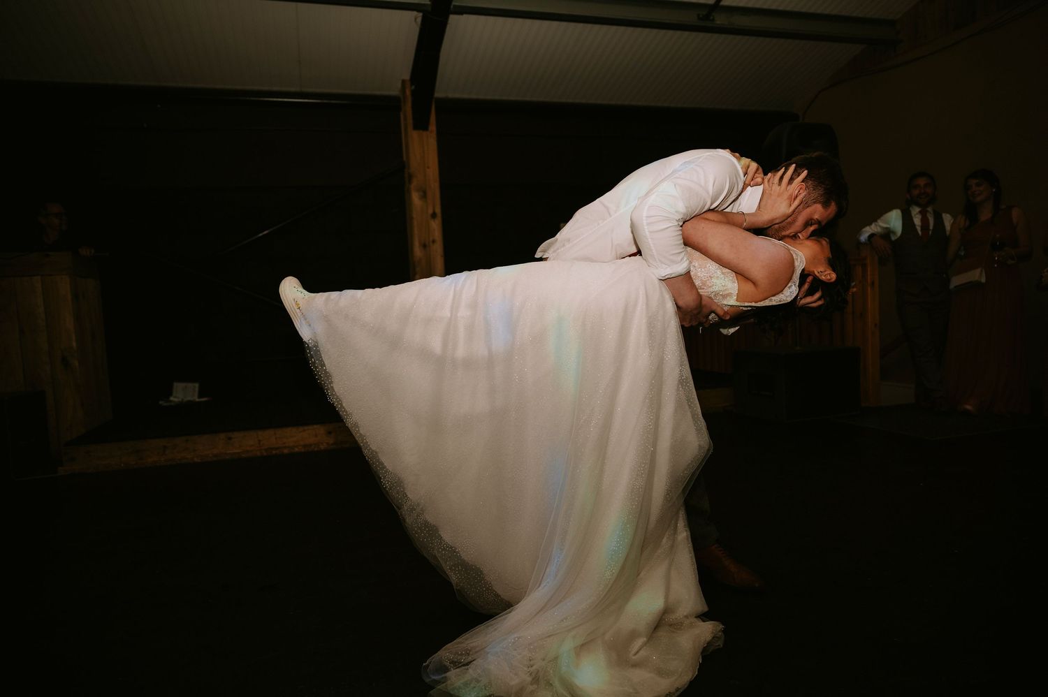A dramatic silhouette of a dancing couple in a dimly lit wedding reception venue.