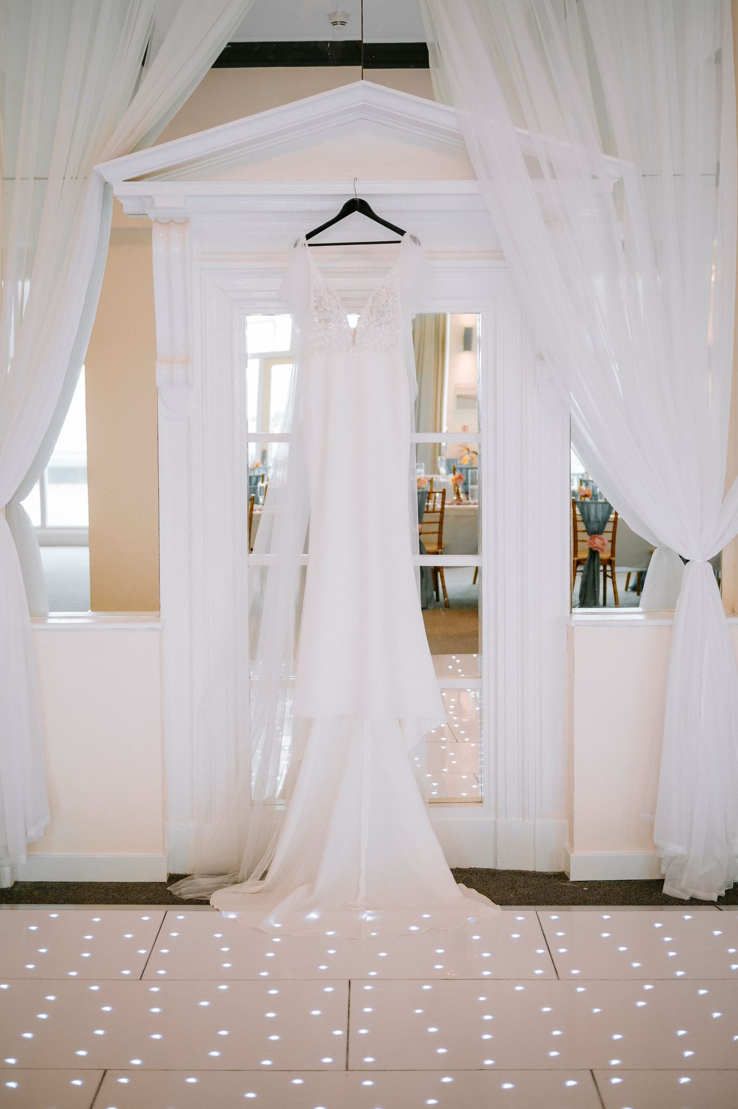 Elegant bridal preparation room with flowing white curtains, natural light, and polka dot carpeting.