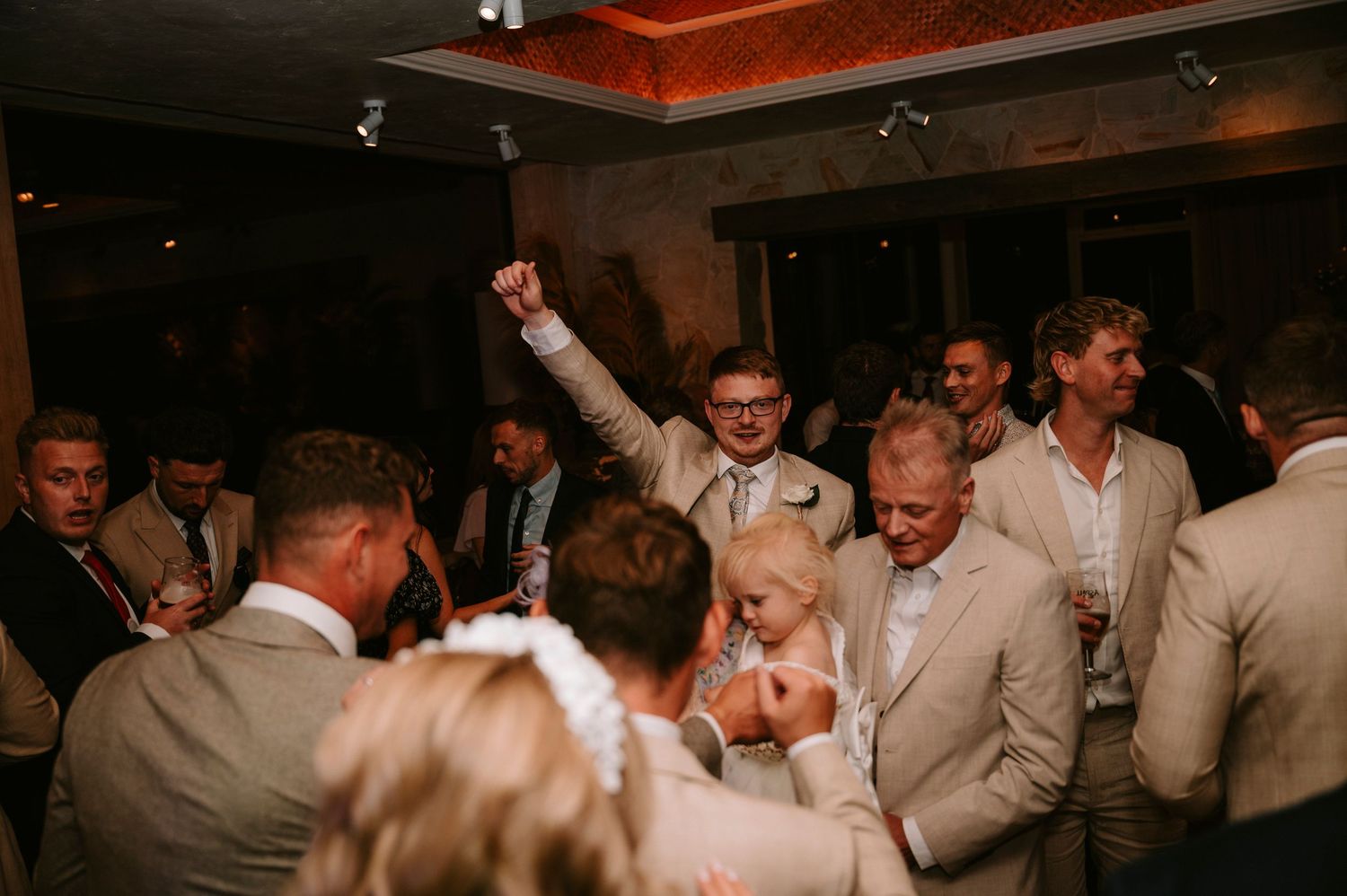 Wedding reception dance party with guests celebrating in formal attire.