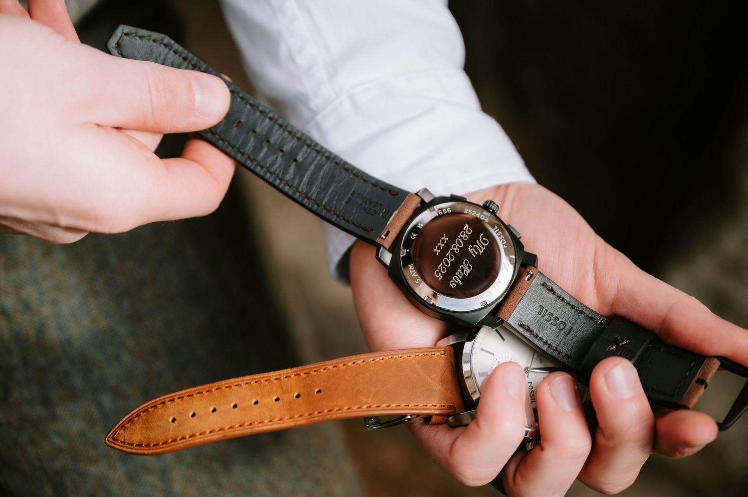 Close-up of hands adjusting a leather watch strap during wedding preparations.