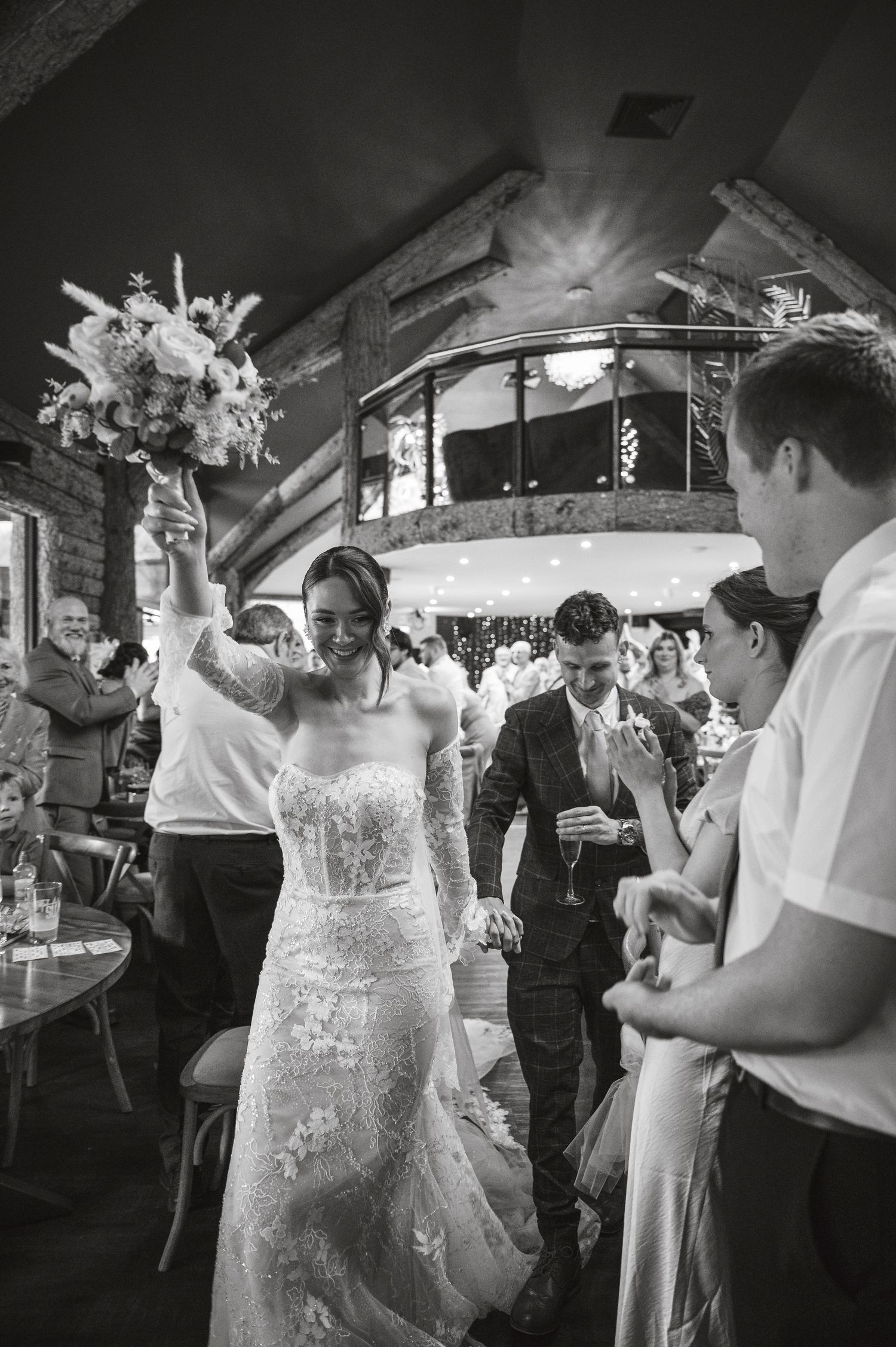 Wedding guests dance and celebrate on a dimly lit dance floor during a lively reception party.
