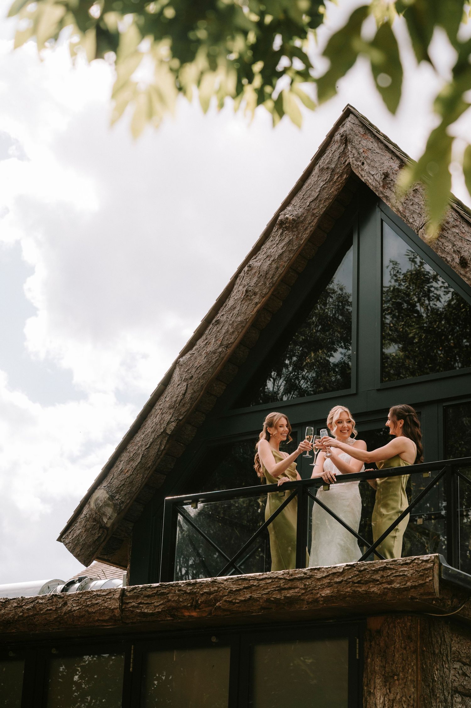 Three people lounging on a wooden deck of a triangular A-frame cabin with a thatched roof.