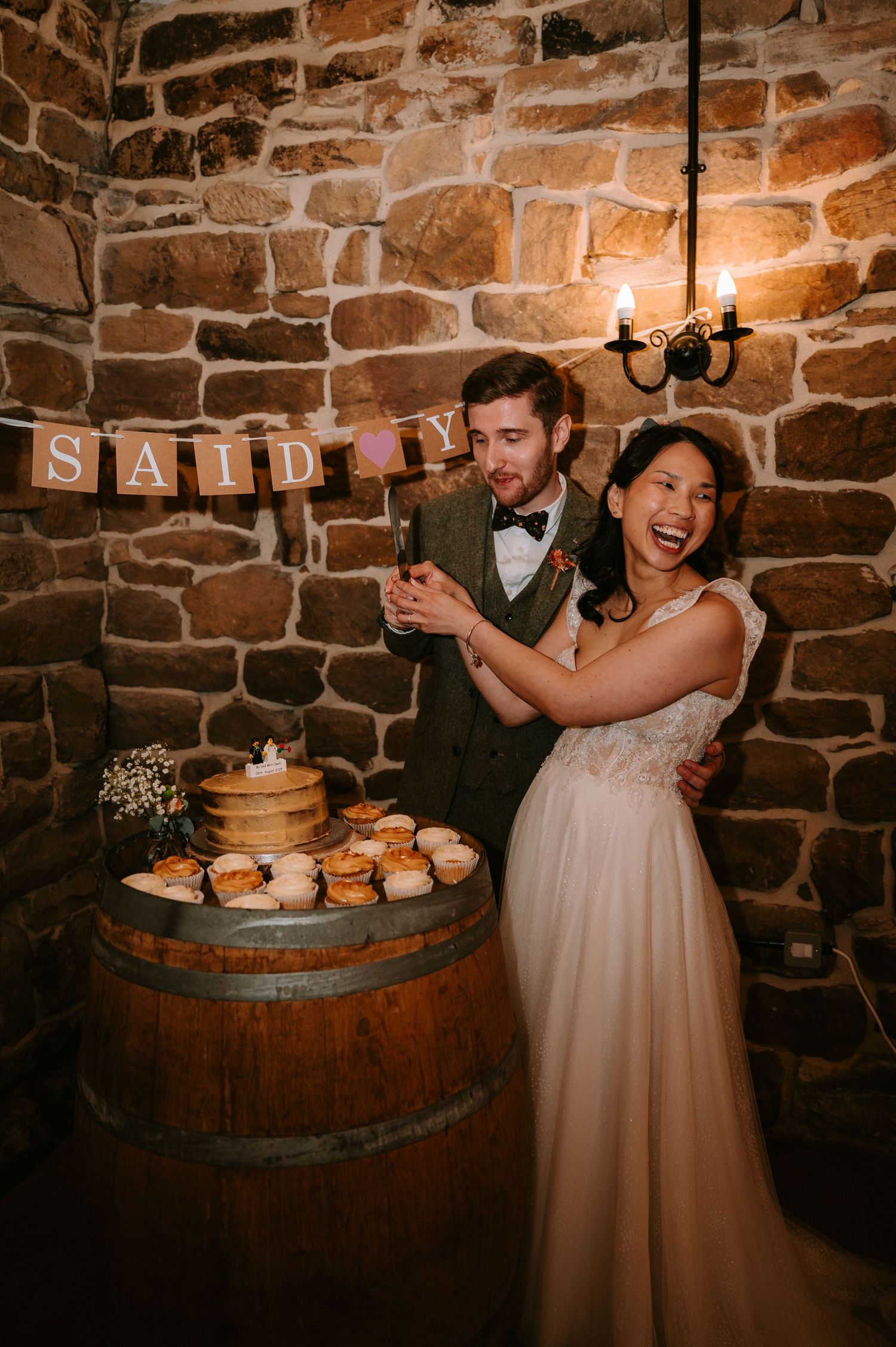 Wedding celebration in rustic stone cellar with wine barrels and cupcakes.