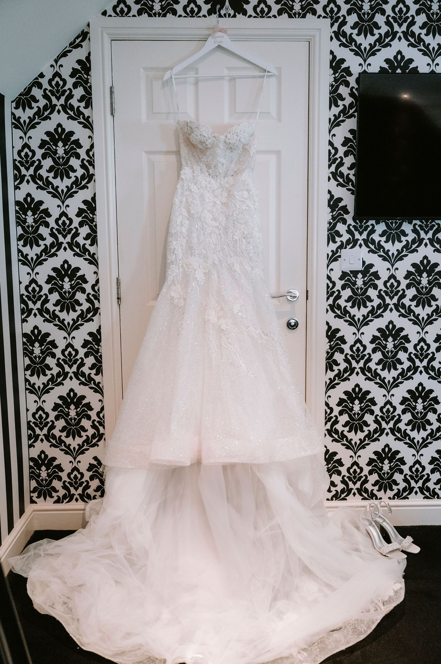 Wedding dress displayed against black and white damask wallpaper.