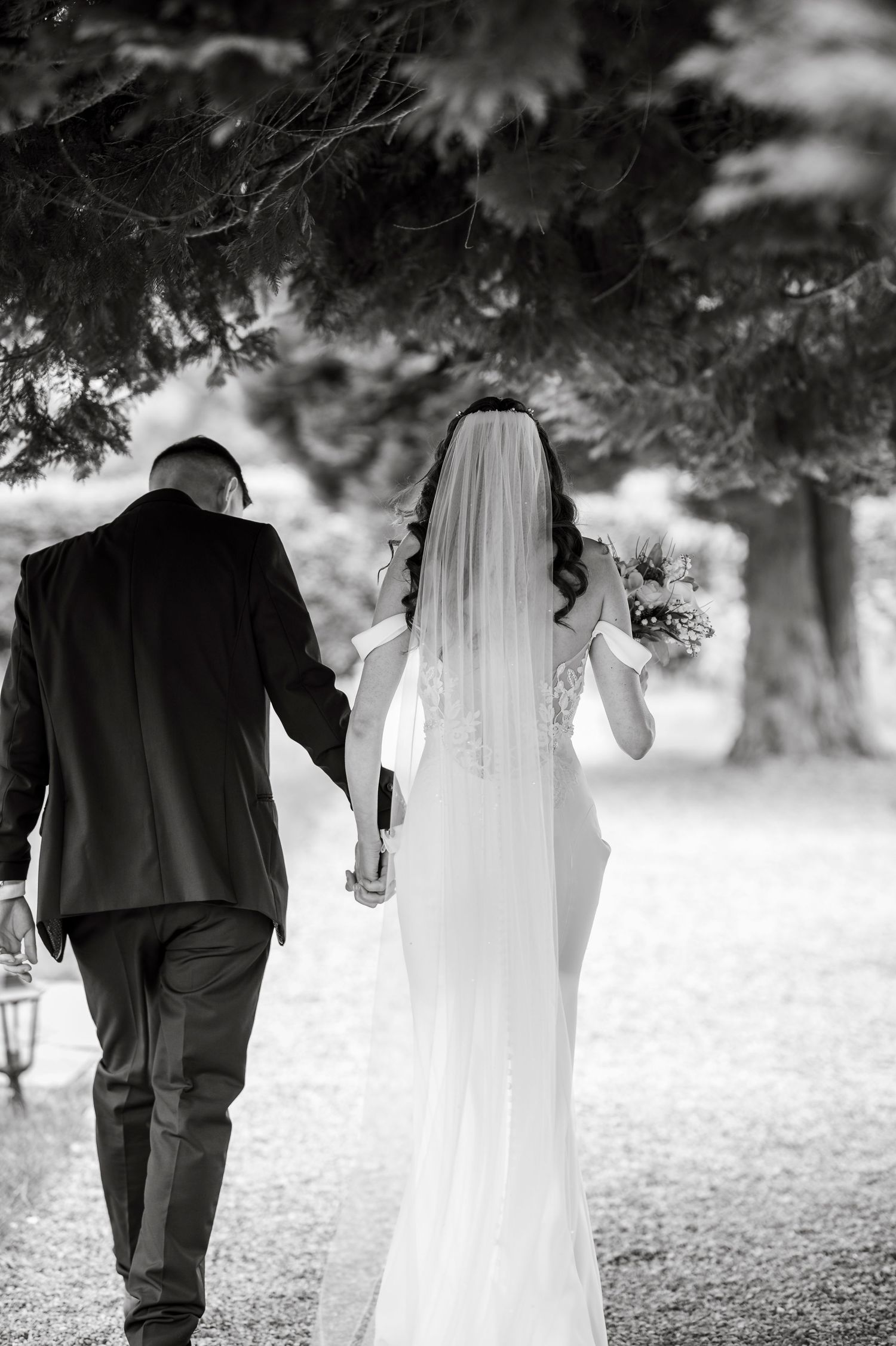 Black and white wedding portrait showing couple walking together outdoors.