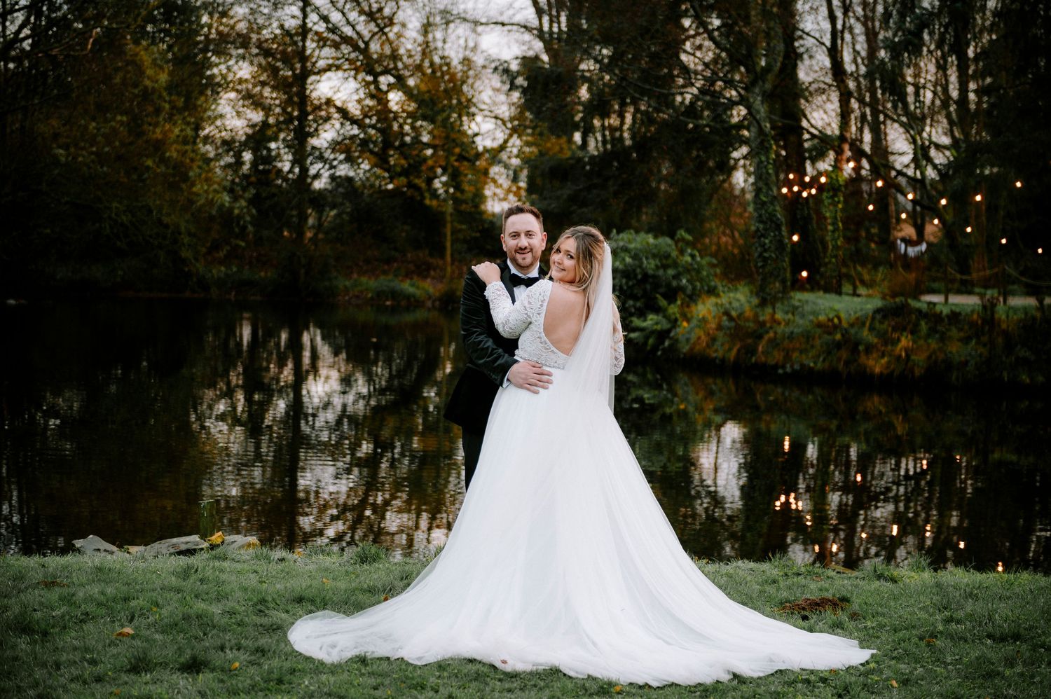 Wedding photography session at dusk with couple posing by a reflective pond.