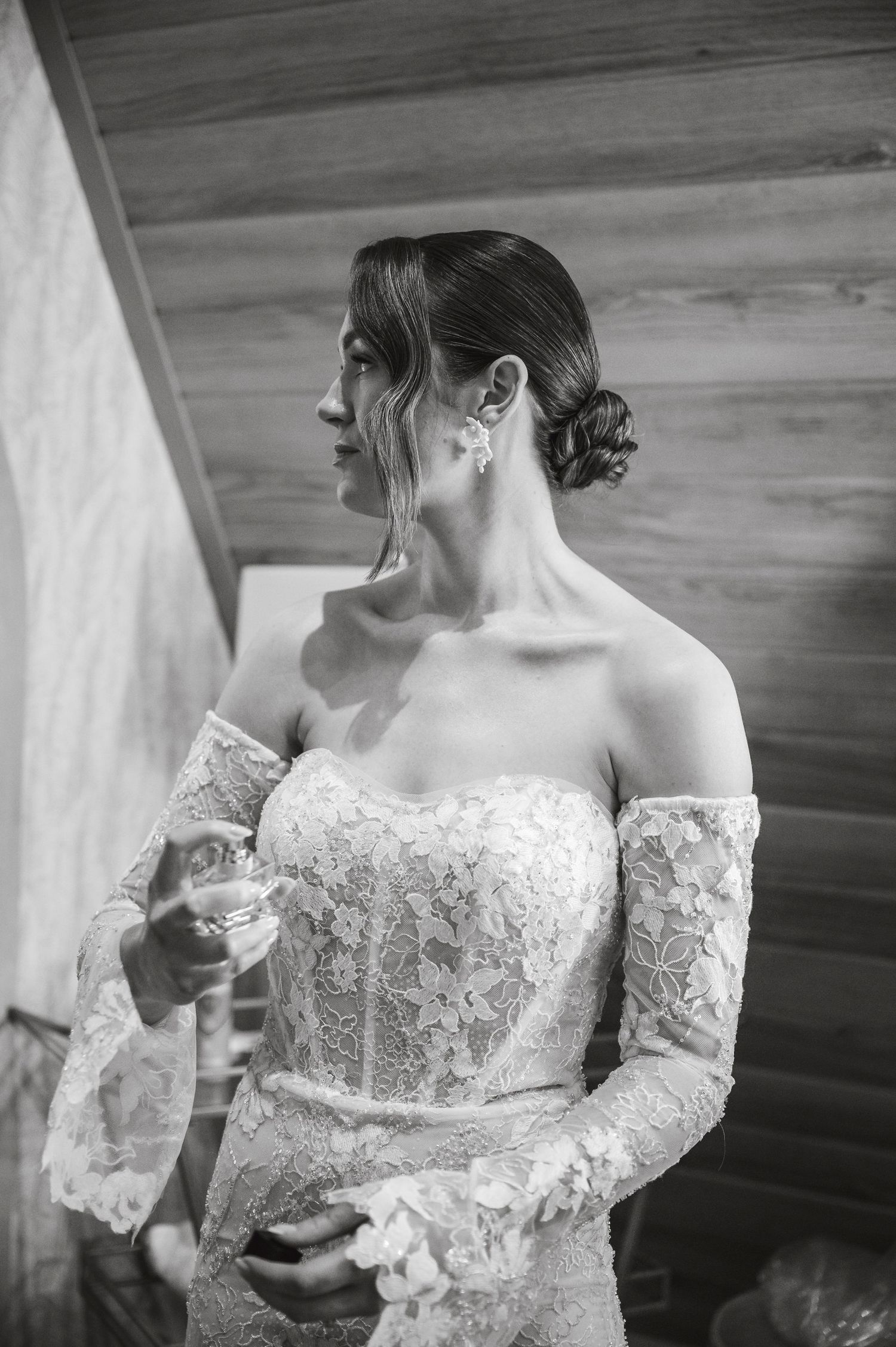 Close-up details of an elegant lace wedding dress with delicate long sleeves and off-shoulder neckline.