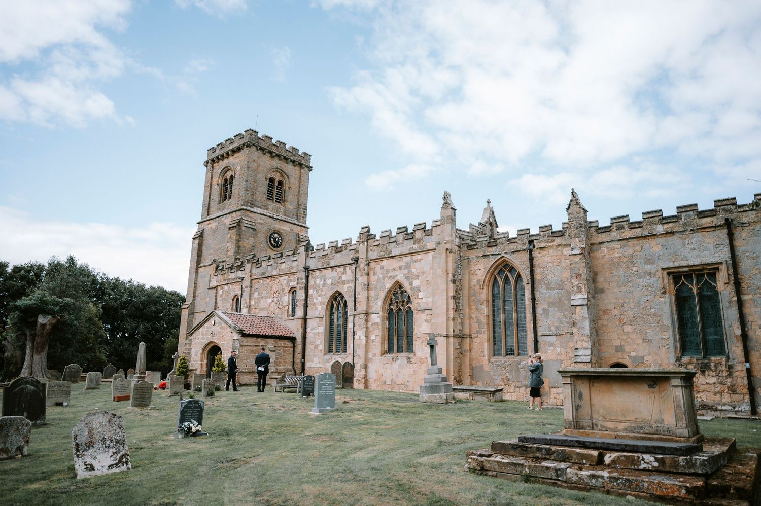 Exterior view of a historic stone church with Gothic architecture and bell tower under blue skies.