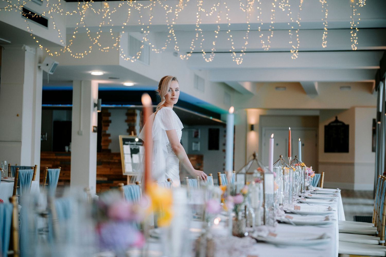 Wedding reception tables set with string lights creating a romantic ambiance.