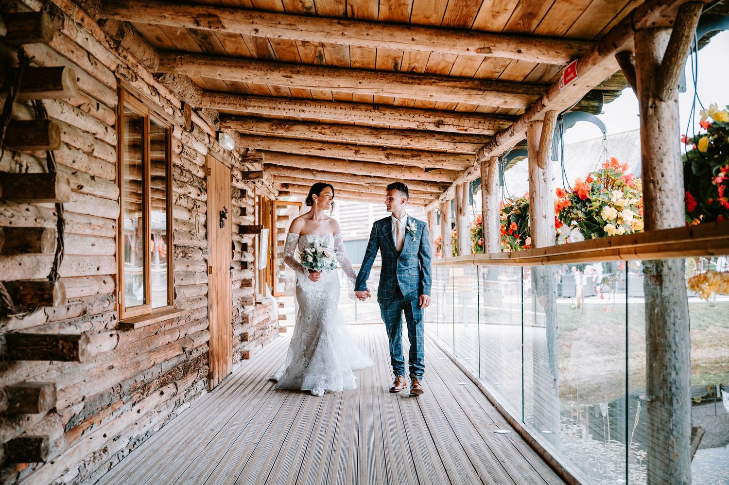 Newlyweds walking together on rustic covered wooden porch with brick walls.