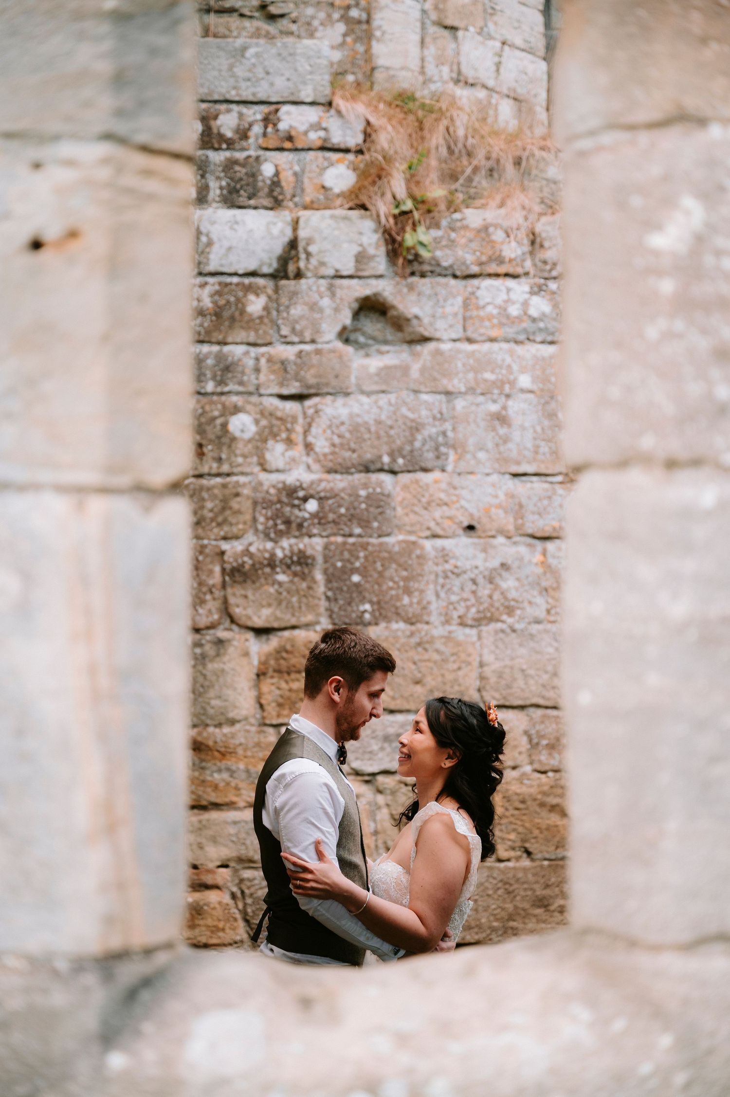 A romantic moment captured against an old stone wall at a wedding venue.