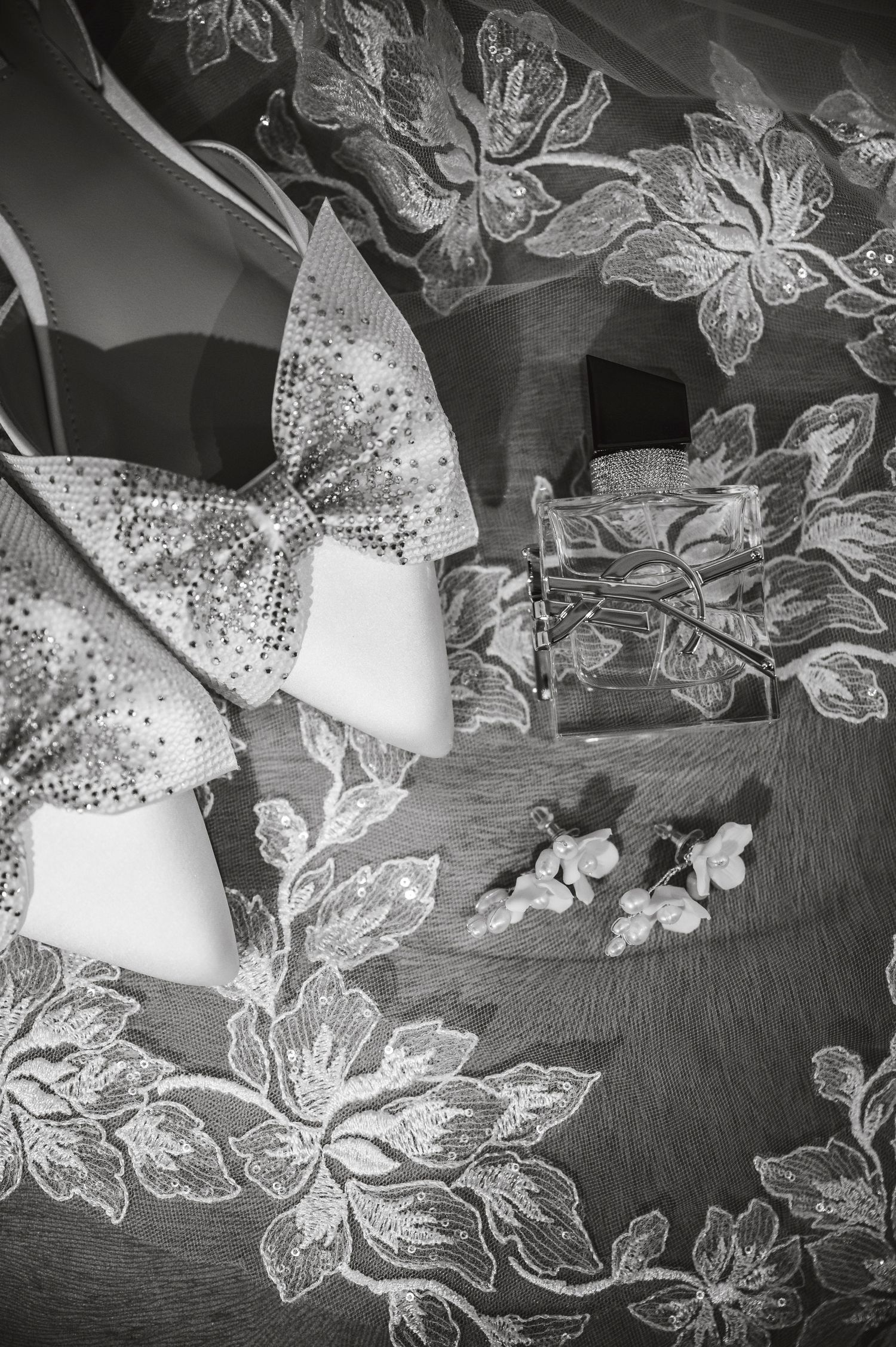 Black and white detail of lace wedding veil with intricate butterfly and floral patterns.