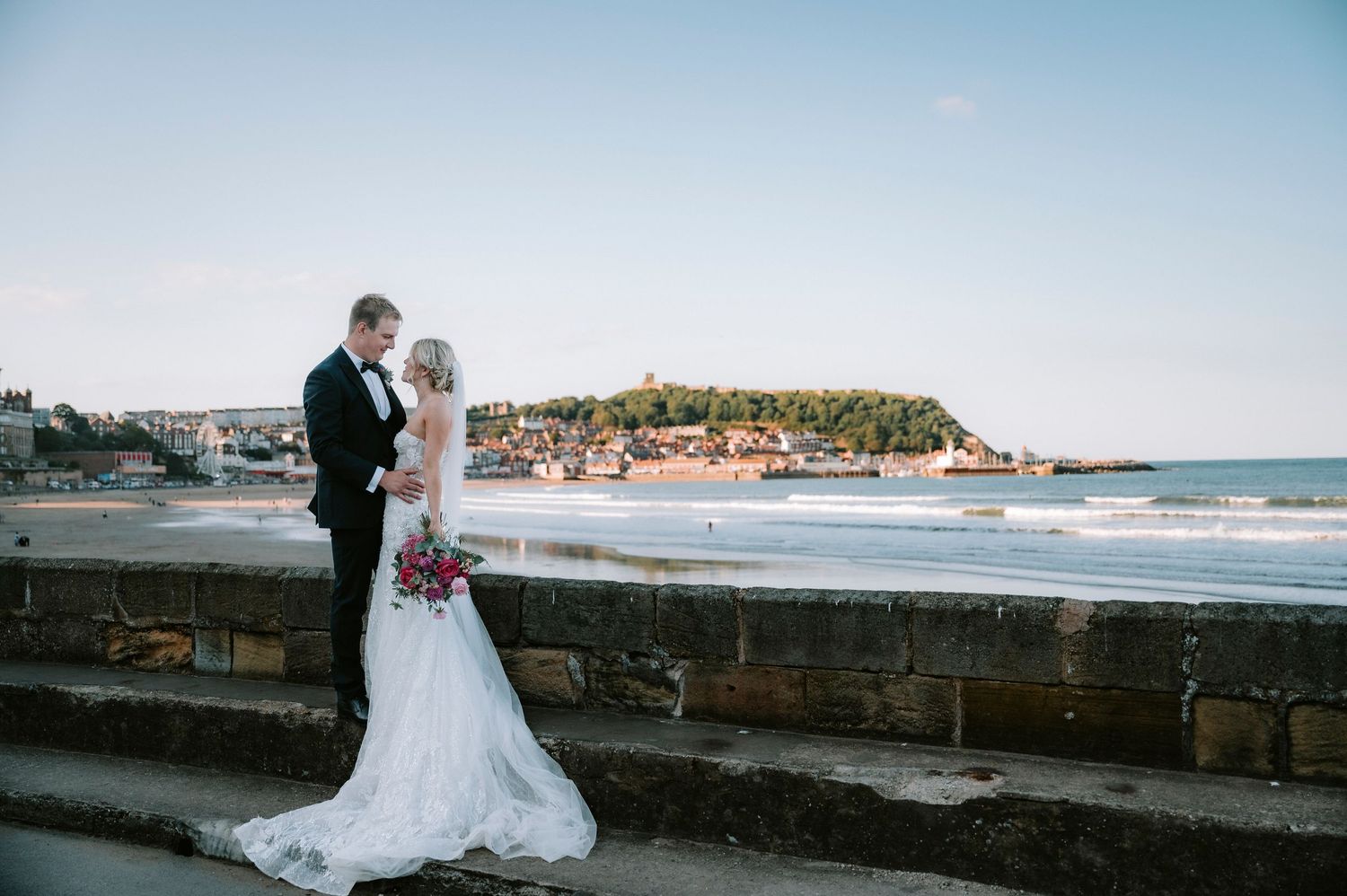 Wedding photos with dramatic coastal backdrop featuring ocean views and stone walls.