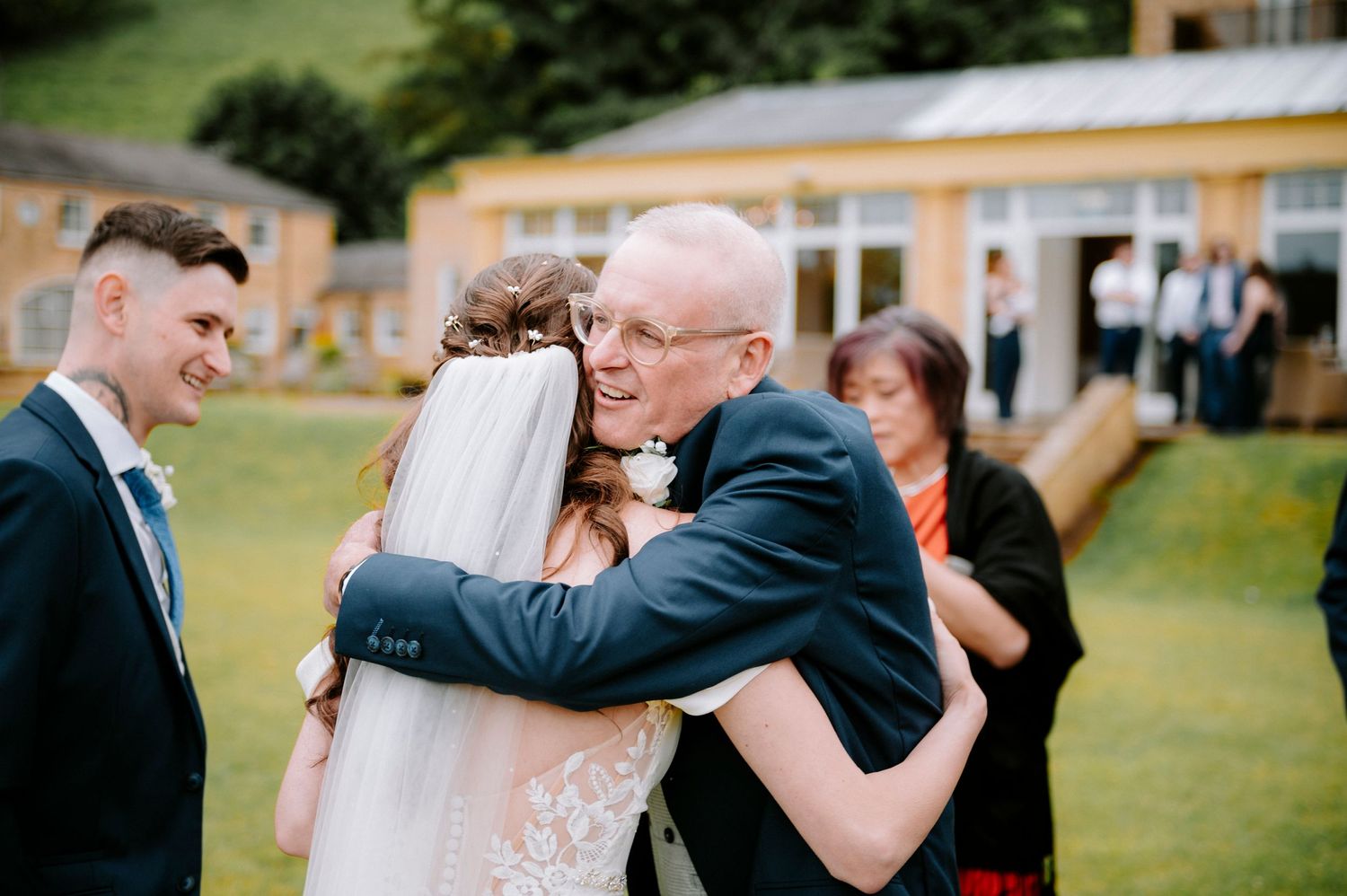 Guests celebrate during outdoor wedding reception near yellow building.