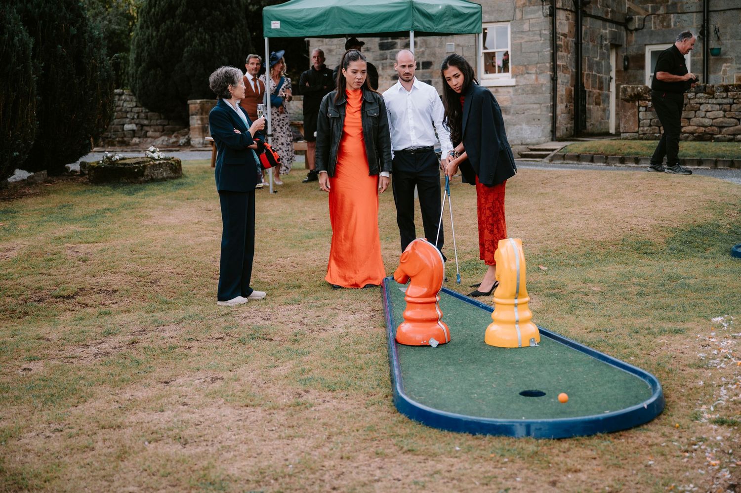 Wedding guests playing outdoor games on a lawn with colorful traffic cones.