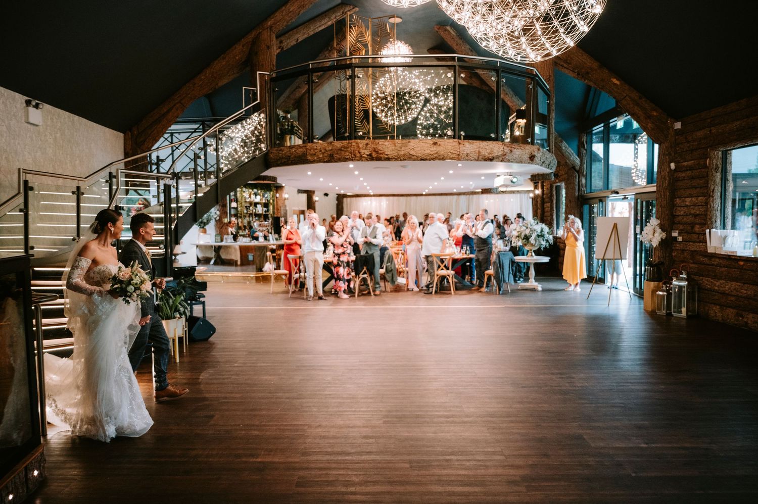A panoramic view of a rustic barn wedding venue with string lights illuminating the dance floor and reception area.