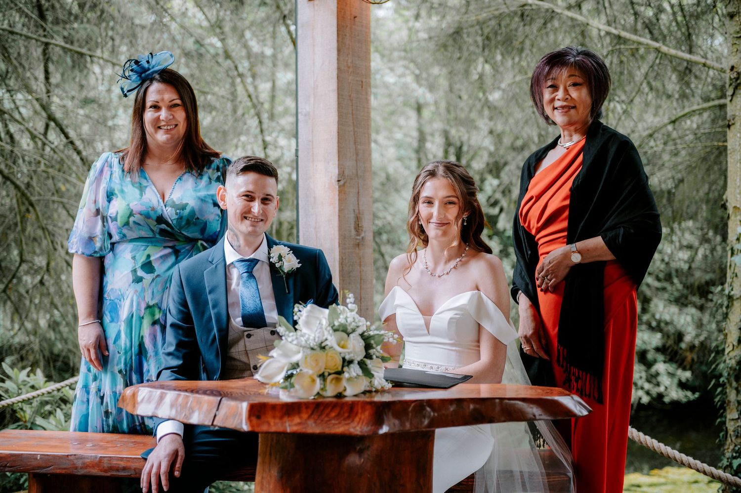 Wedding guests gathered around wooden tables during document signing ceremony.