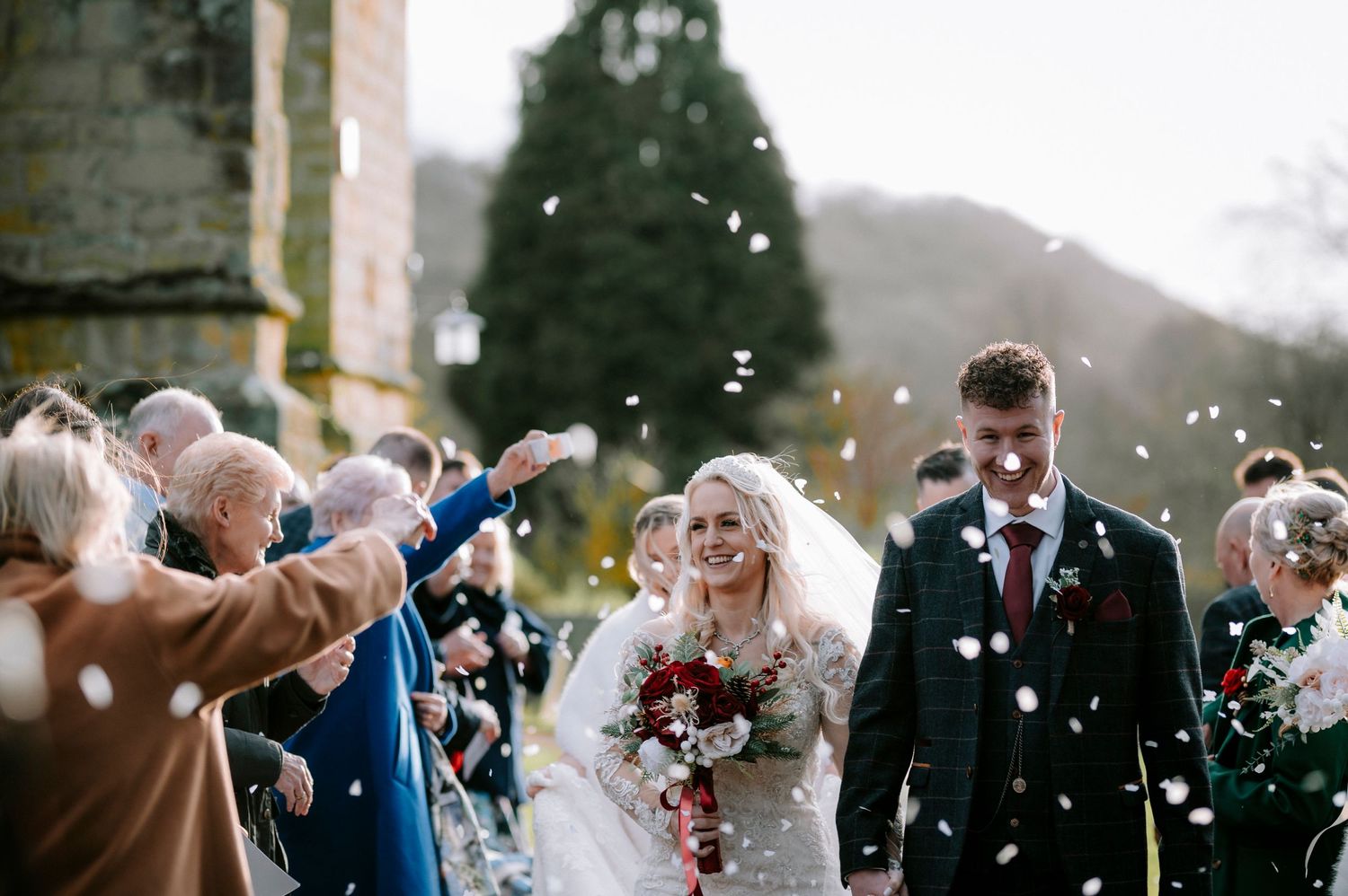 Wedding guests shower the newlyweds with confetti during an outdoor celebration.