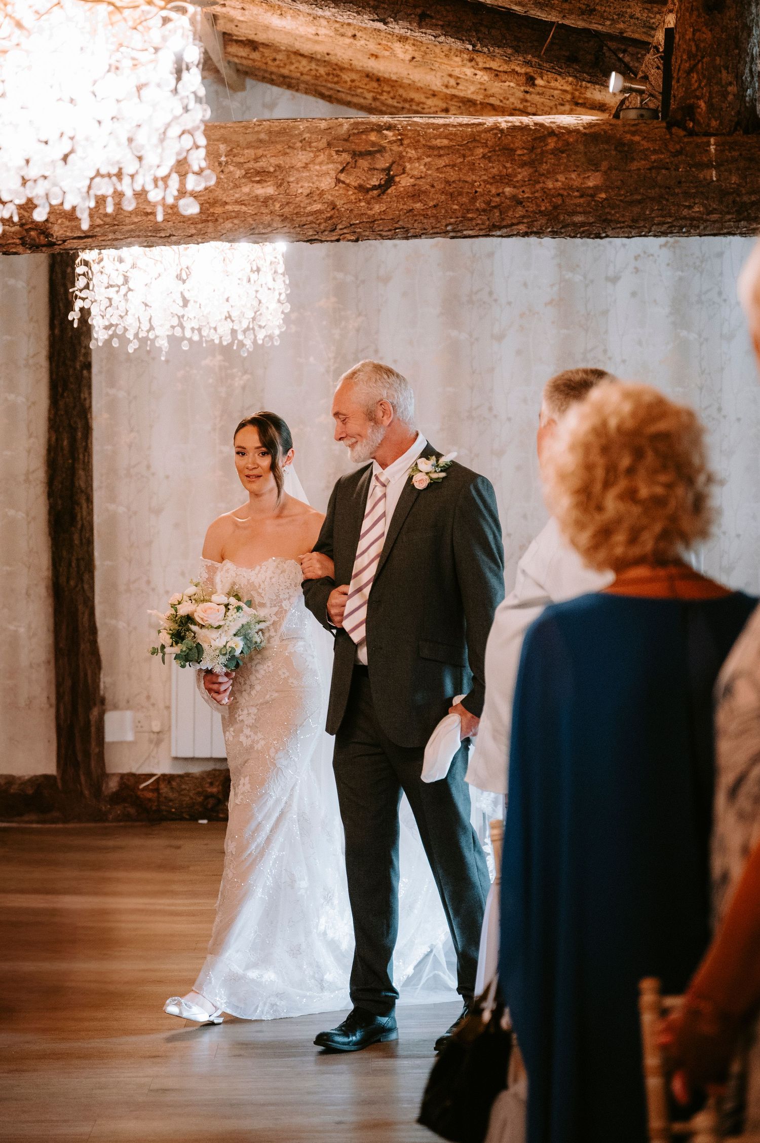 Wedding ceremony candid moments in rustic indoor venue with wooden beams.