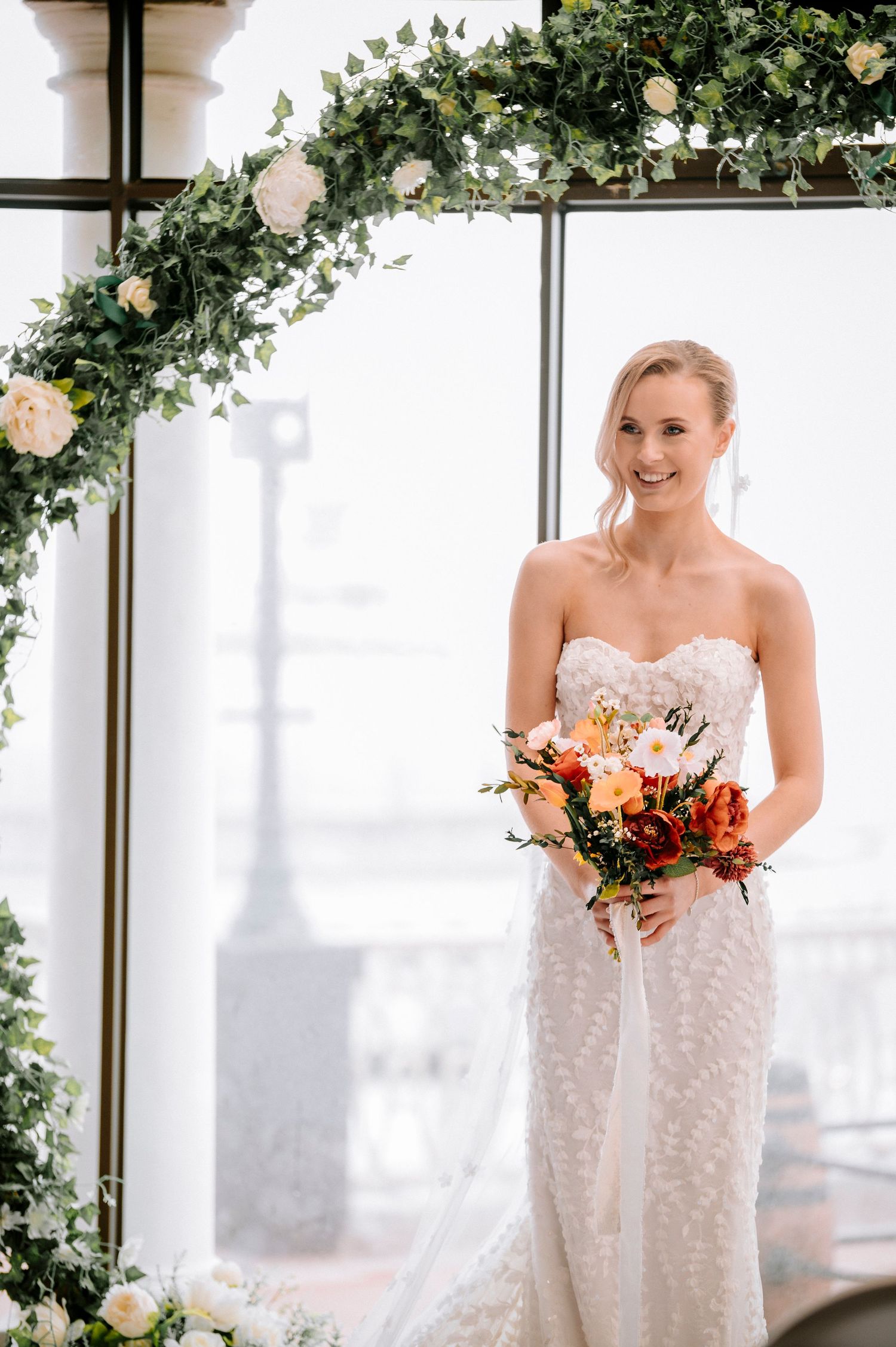 An elegant strapless wedding gown with delicate floral appliques in a bright indoor setting.