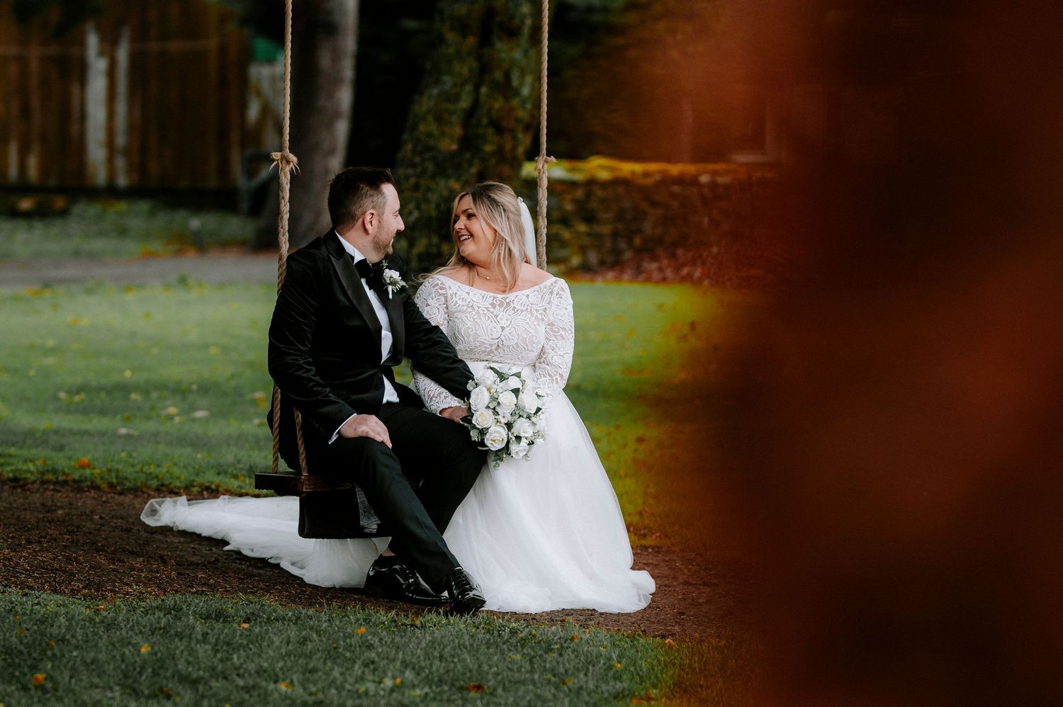 Wedding couple poses together in a romantic outdoor setting with warm autumn lighting.