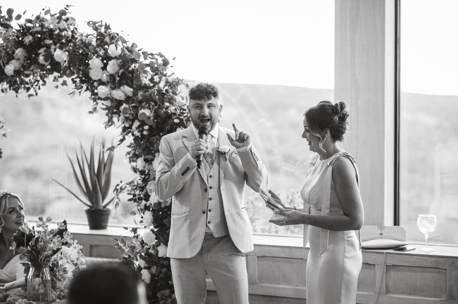 Black and white photo of wedding party members celebrating by a window.
