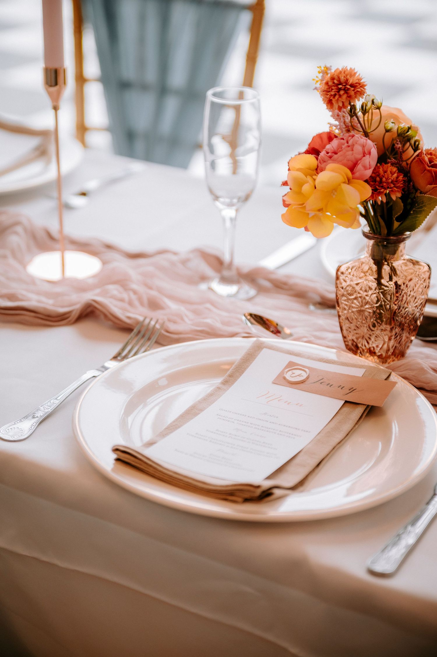 Elegant table setting with copper vases, white plates, and coral floral arrangements.