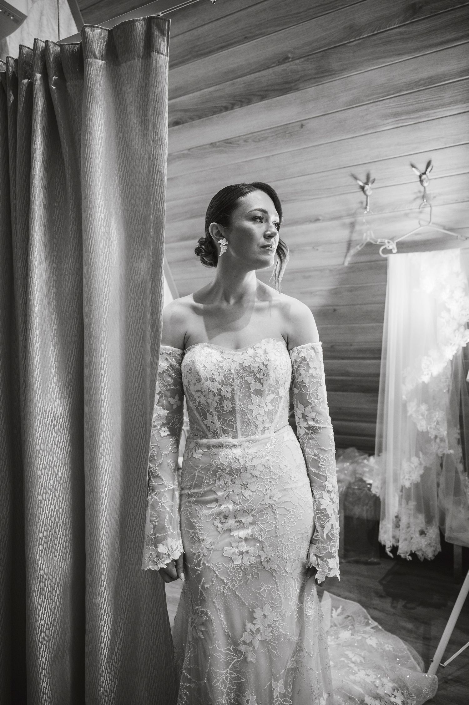 Row of elegant white lace wedding dresses displayed on hangers in a bridal boutique.