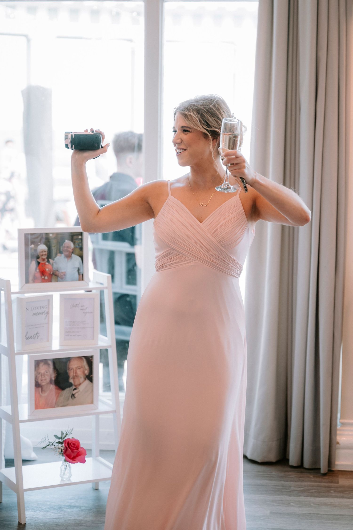 Bridesmaids in blush pink dresses getting ready in a bright hotel room with mirrors.