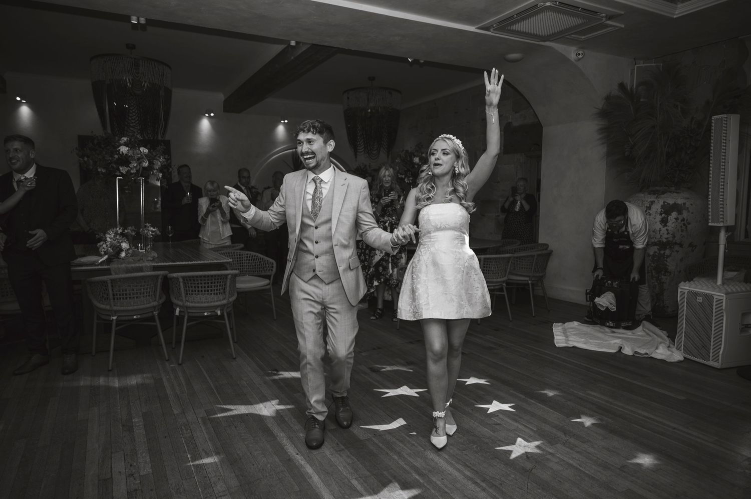 Black and white photo of couple dancing energetically at wedding reception.