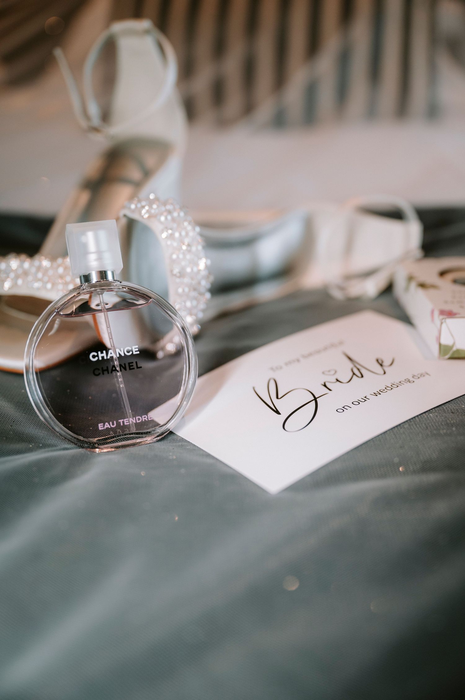 Chanel perfume bottle and wedding details arranged on soft gray fabric with delicate name cards.