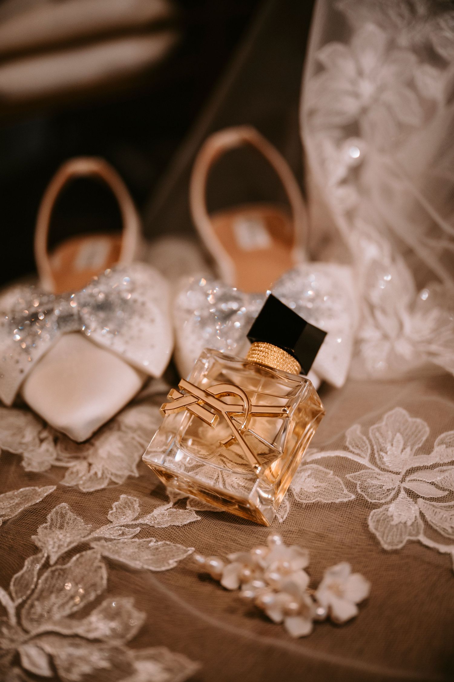 Delicate lace wedding accessories and details arranged on wooden surface.
