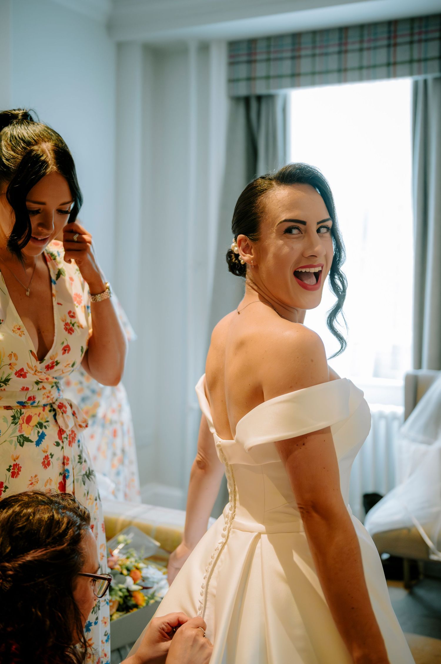 Candid moments of wedding preparation showing laughter and joy while getting dressed.