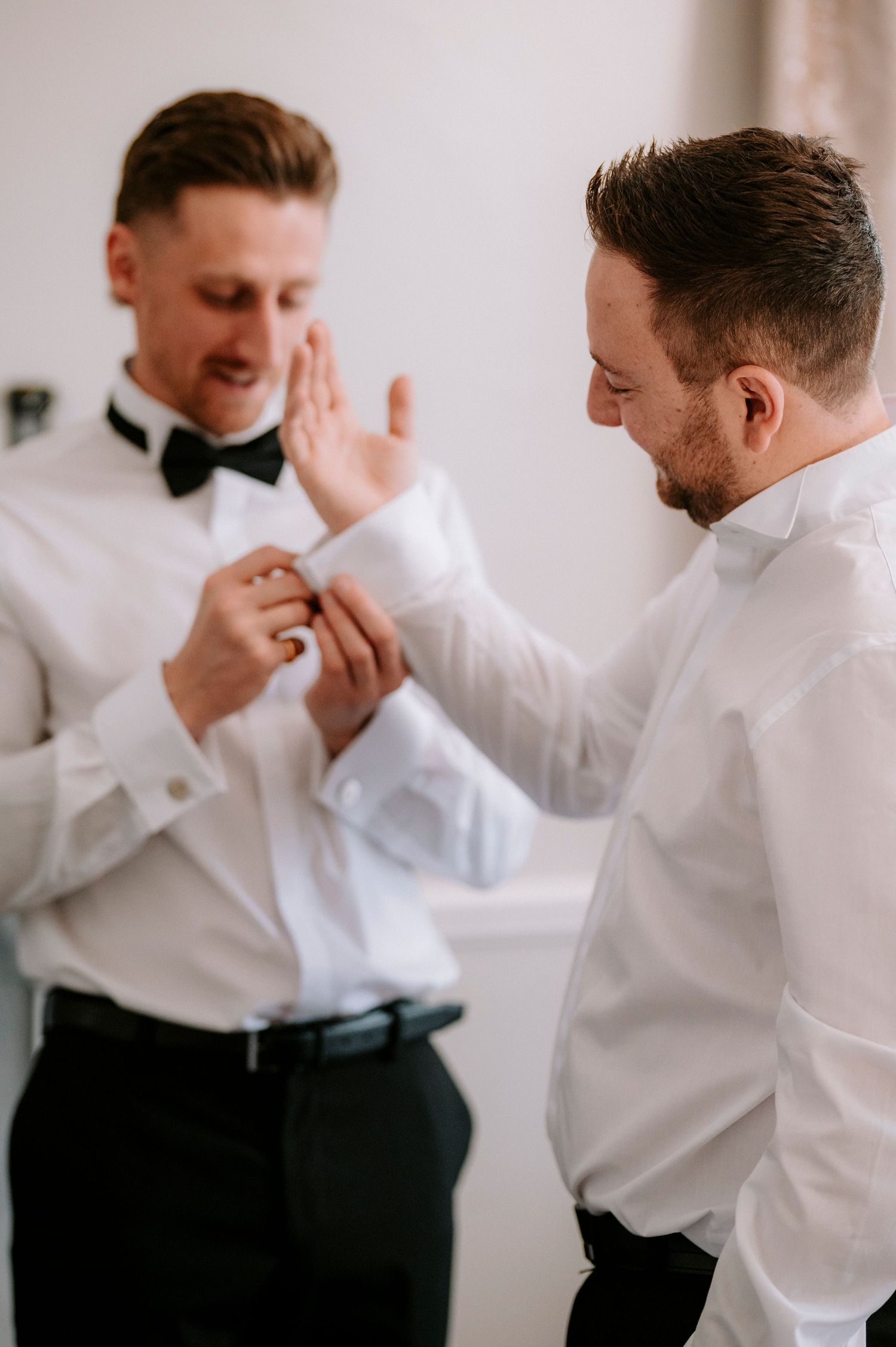 Groomsmen in formal attire share animated conversations and laughter before the ceremony.