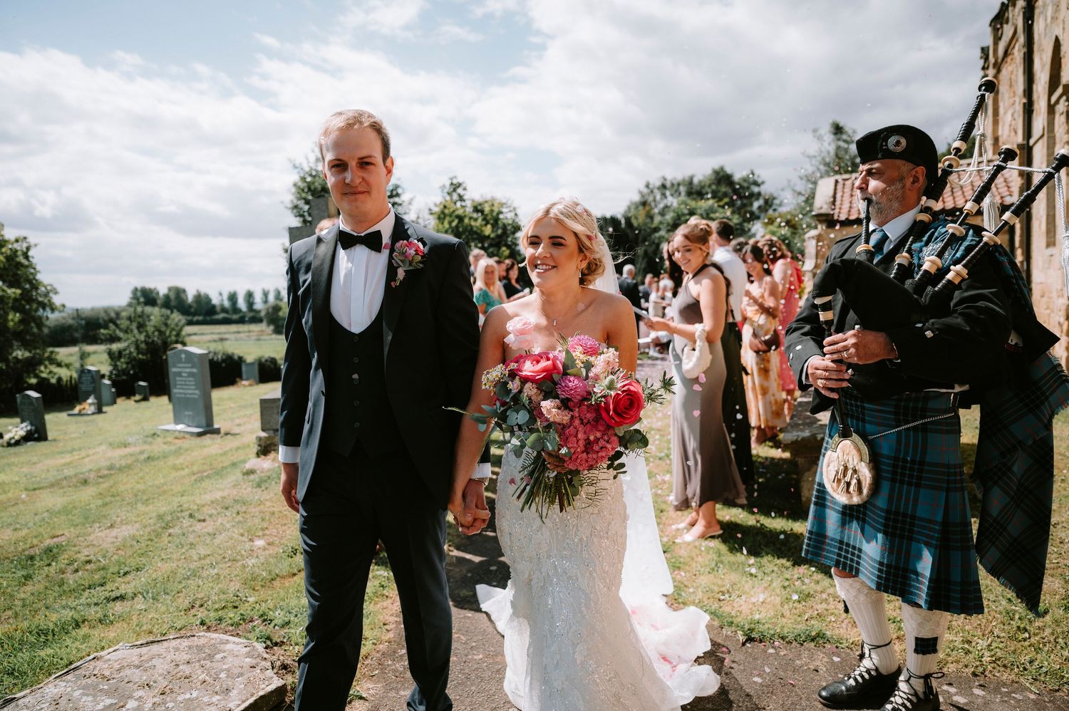 Wedding guests gather outside a rustic stone building for celebration photos.