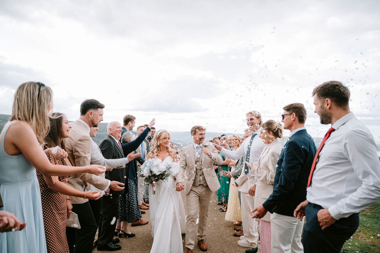 Wedding guests gathered in a celebration line at an outdoor reception venue.