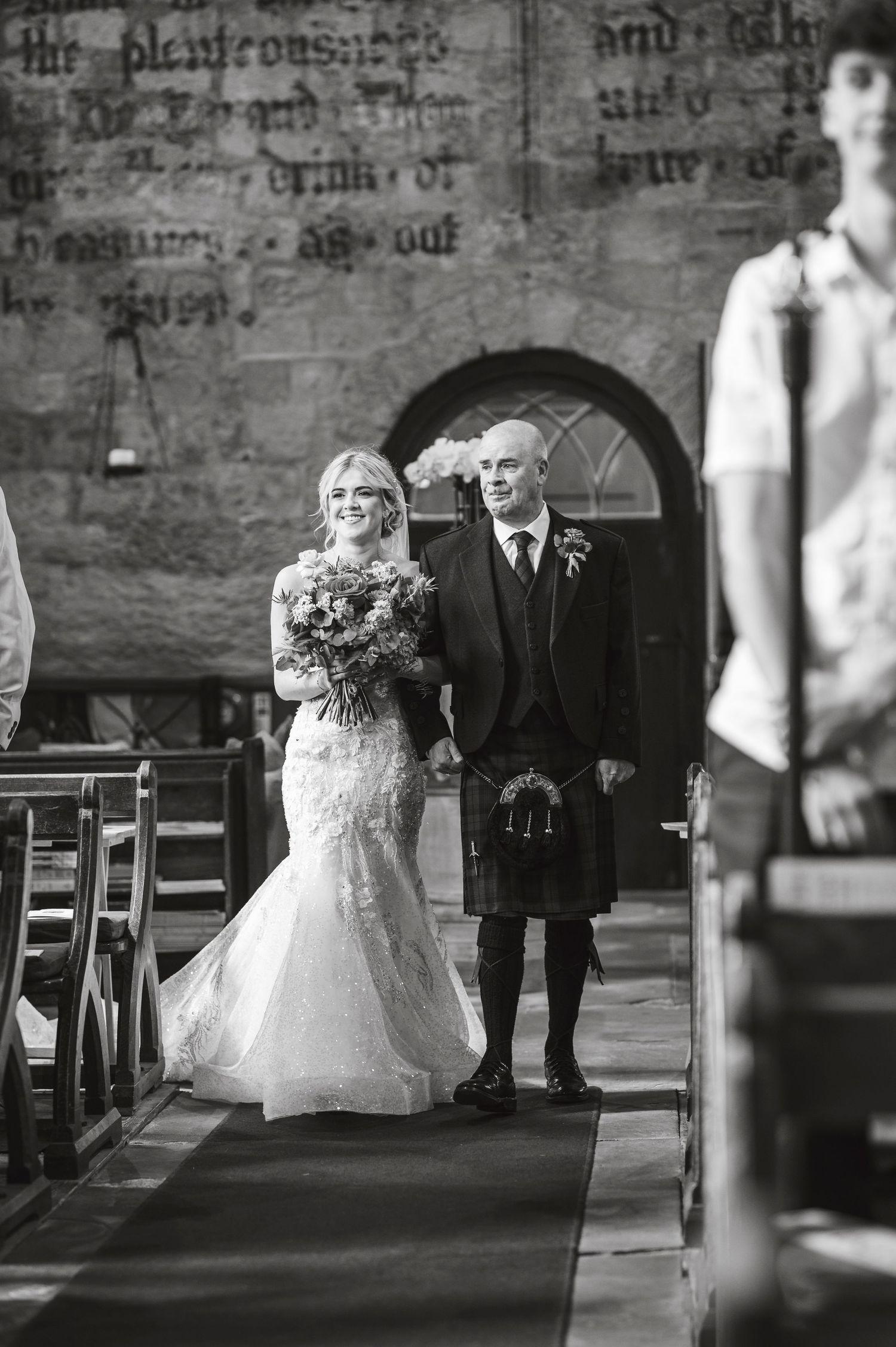 Black and white photo of wedding ceremony in historic church with stone walls.