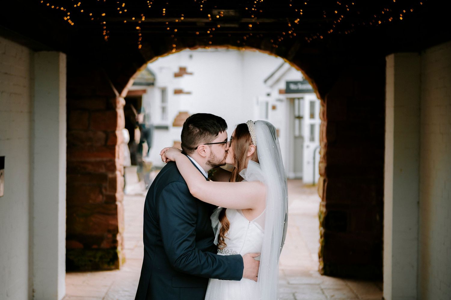 Intimate wedding moments captured through architectural arches with dramatic lighting.