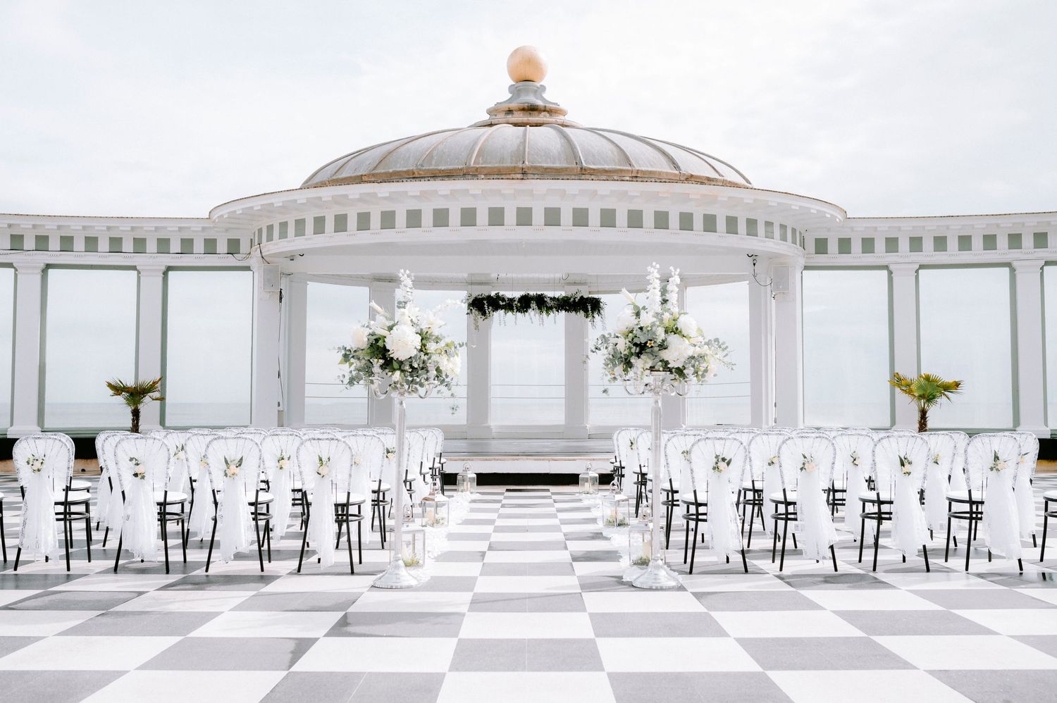 Elegant white wedding ceremony space with checkered floor and domed ceiling.