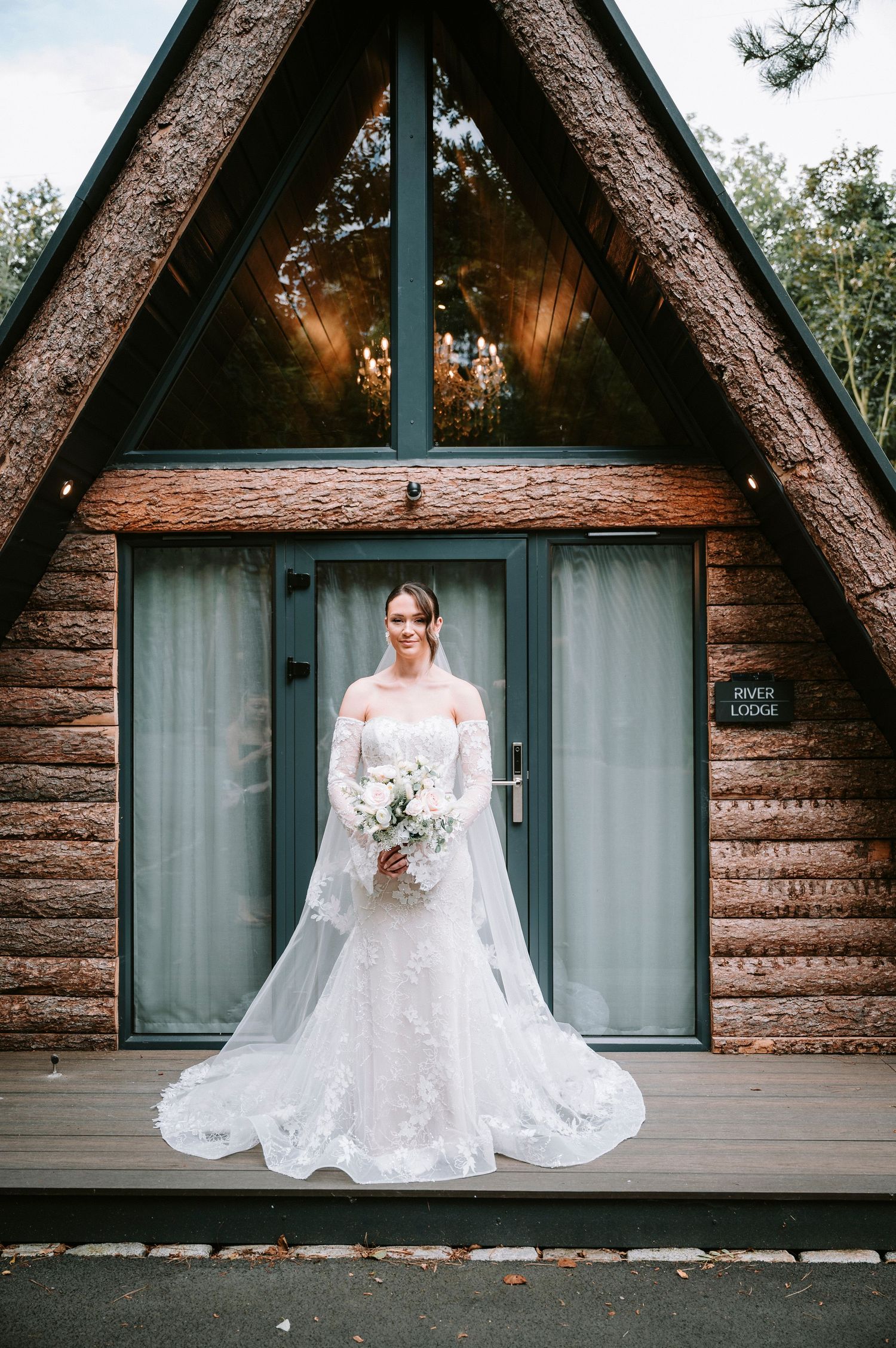 A rustic A-frame cabin serves as backdrop for wedding portraits.
