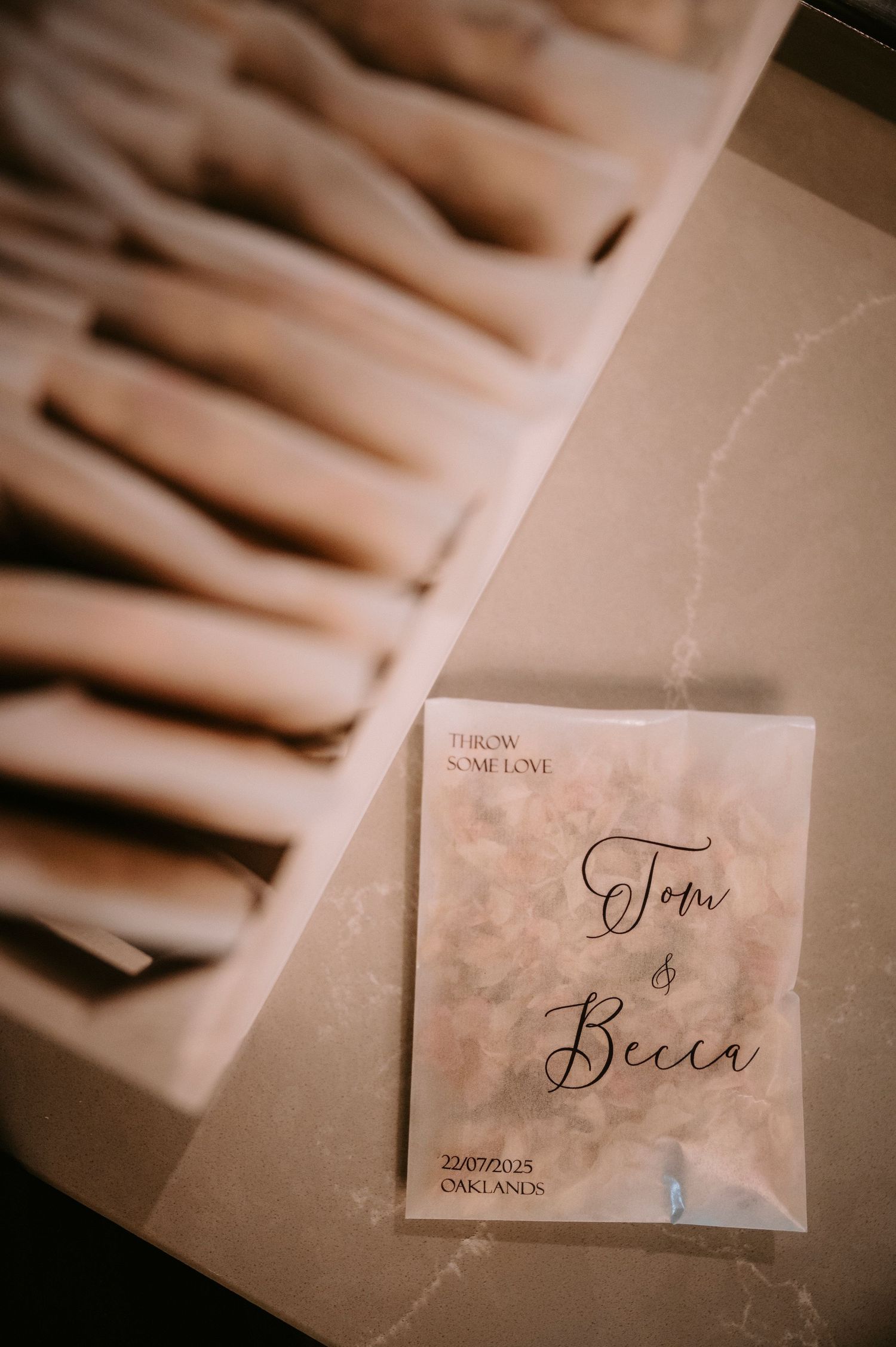 Wedding place cards with elegant calligraphy names displayed in a soft, sepia-toned photograph.