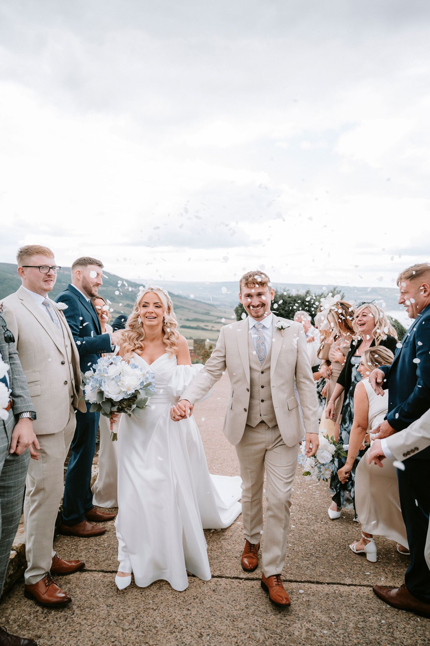 Wedding party celebrating outdoors with guests in beige and navy attire.