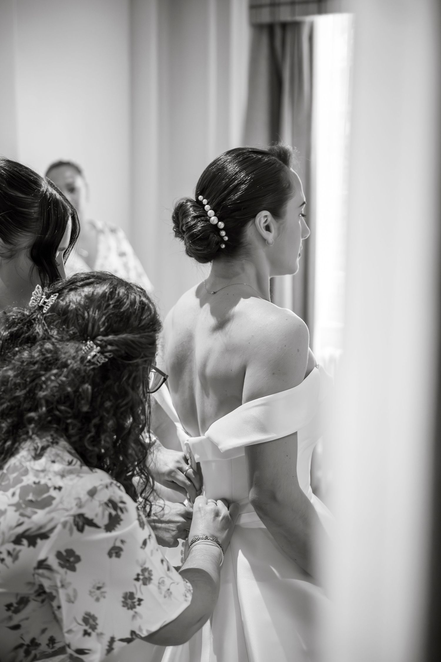 Black and white image of wedding day preparations with soft window light.