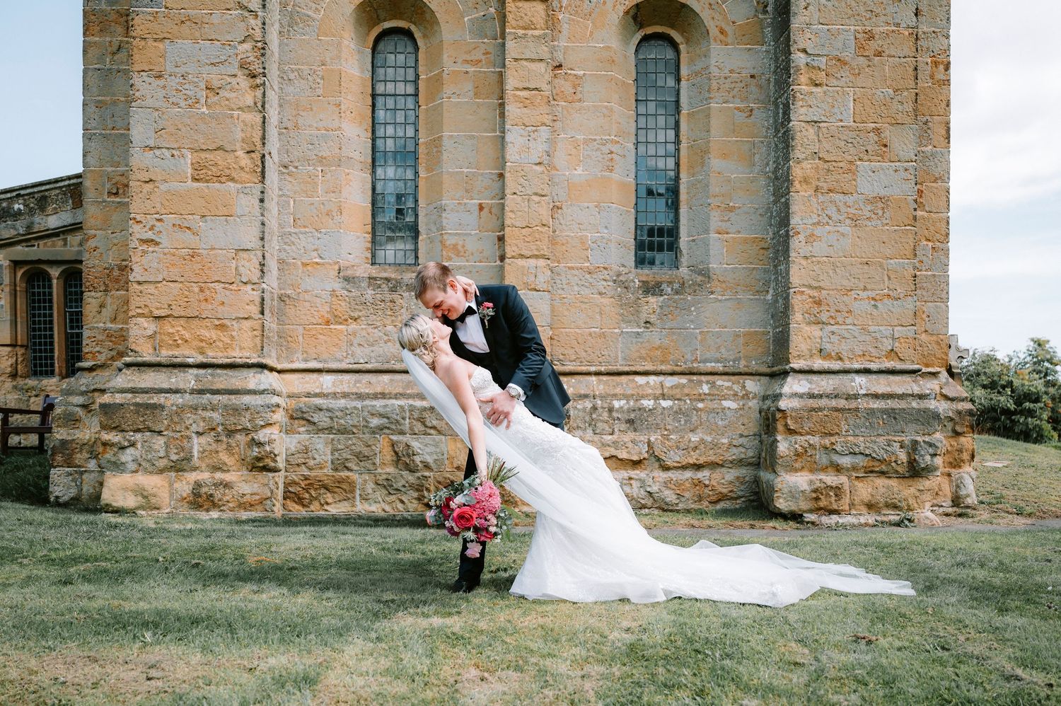 Elegant wedding scene with cathedral and flowing white veil in natural light.