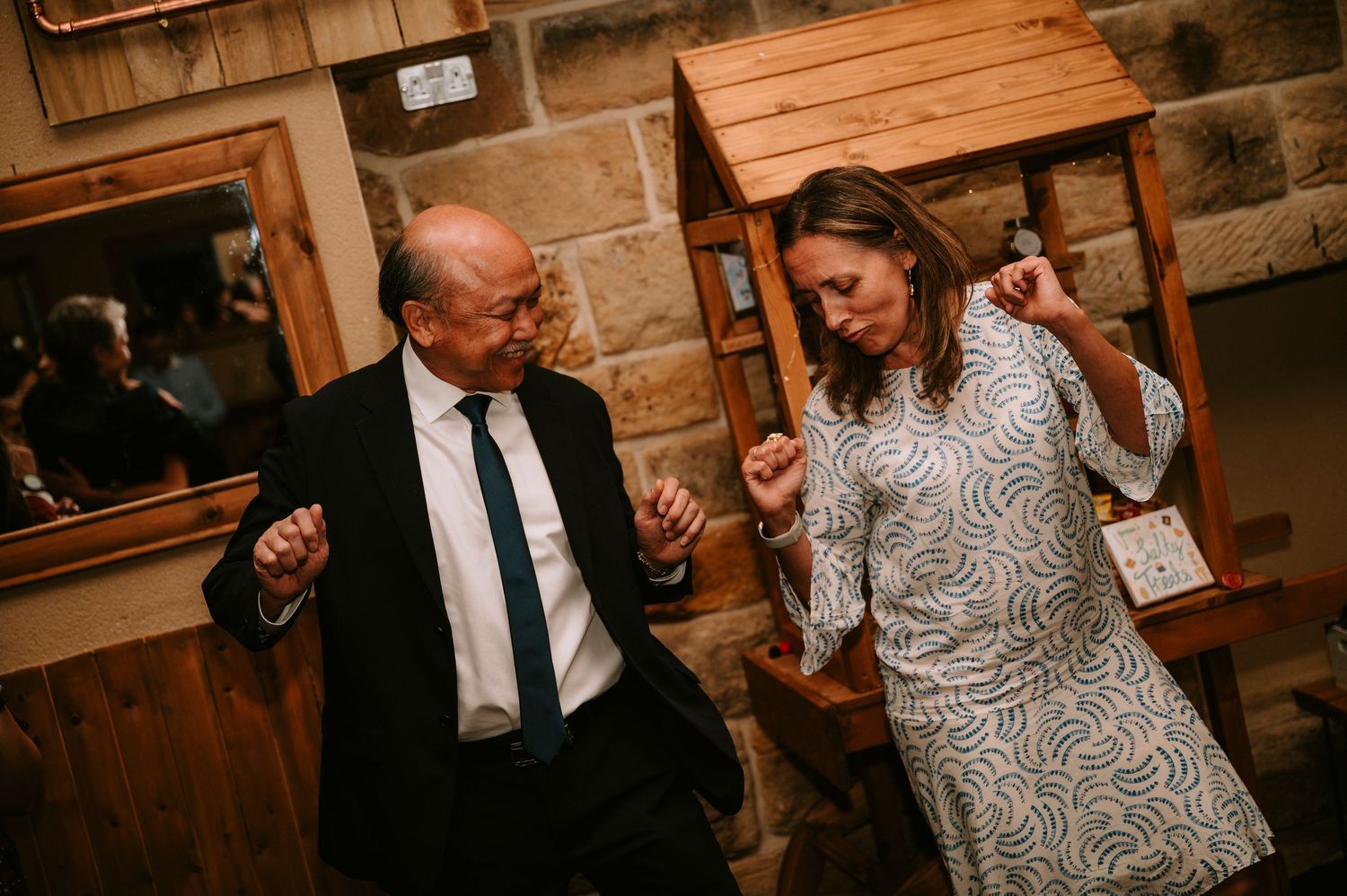 Wedding guests dancing and celebrating at a rustic indoor reception venue.