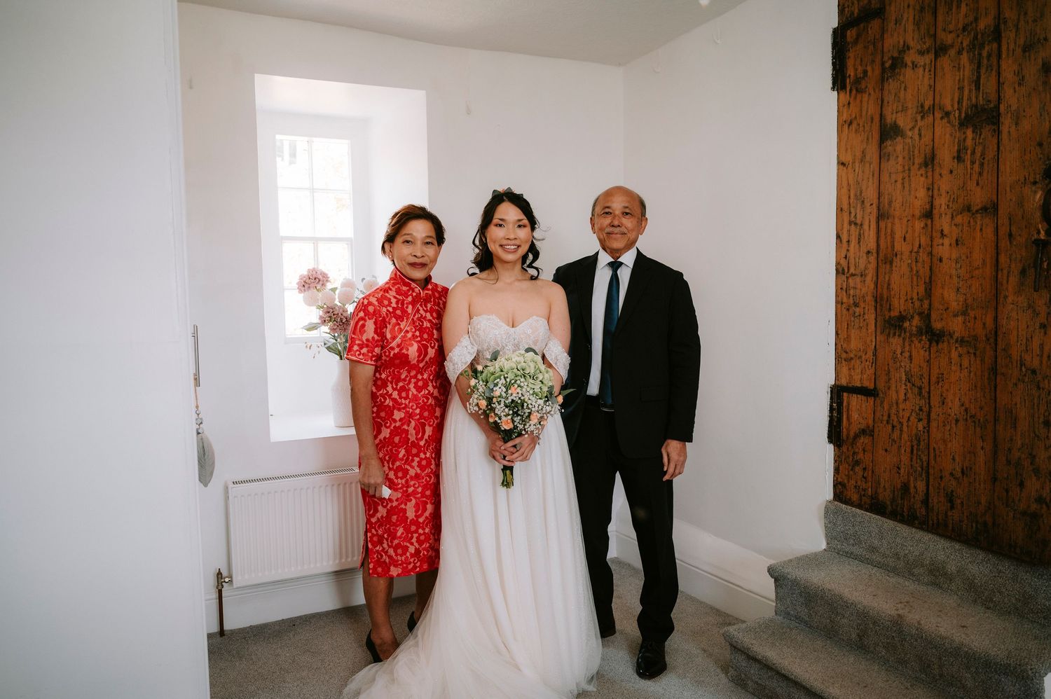 Wedding party gathering in white interior with wooden door details.