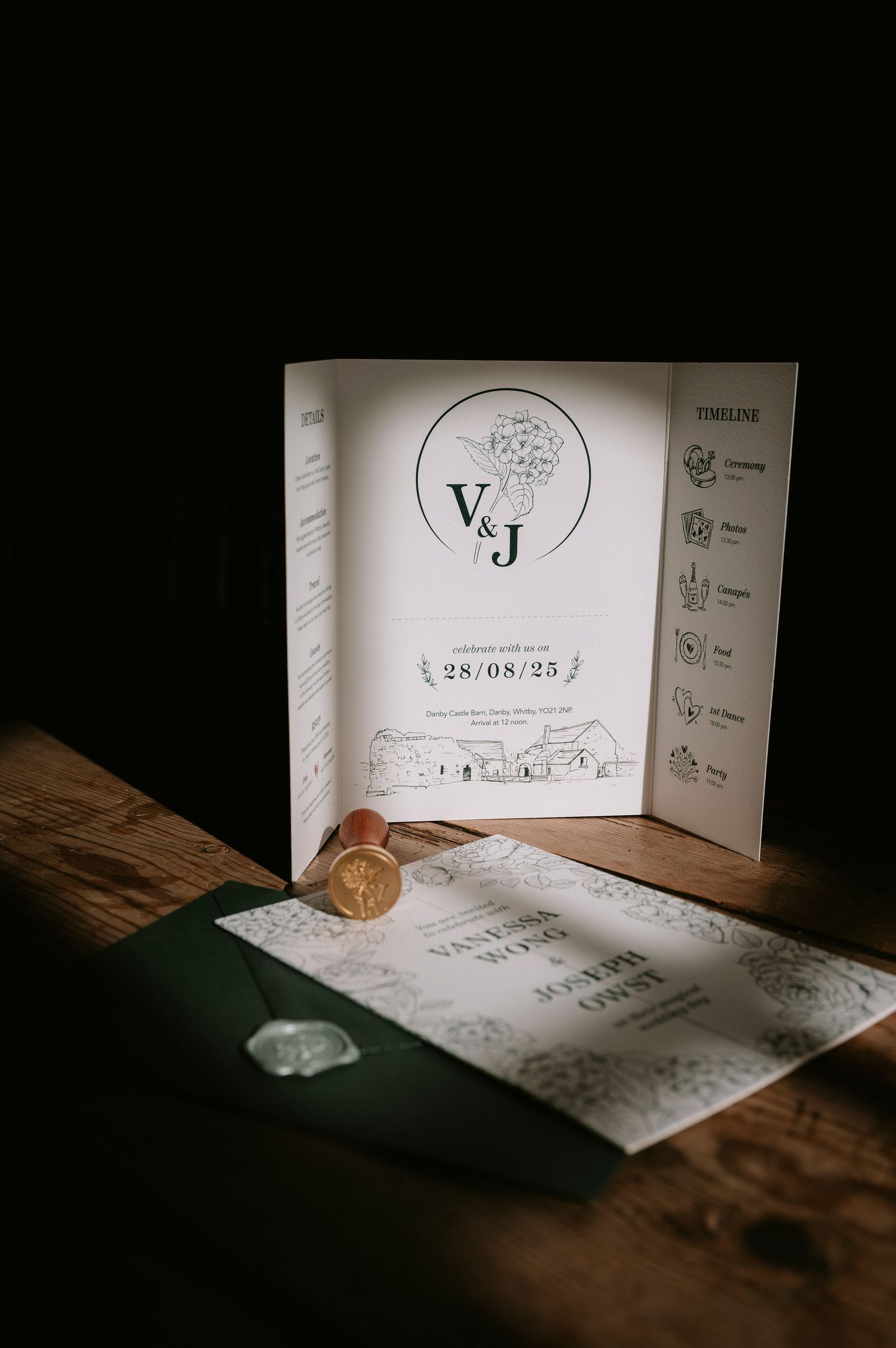 Wedding invitation cards with custom designs and wax seals displayed on a rustic wooden surface in moody lighting.