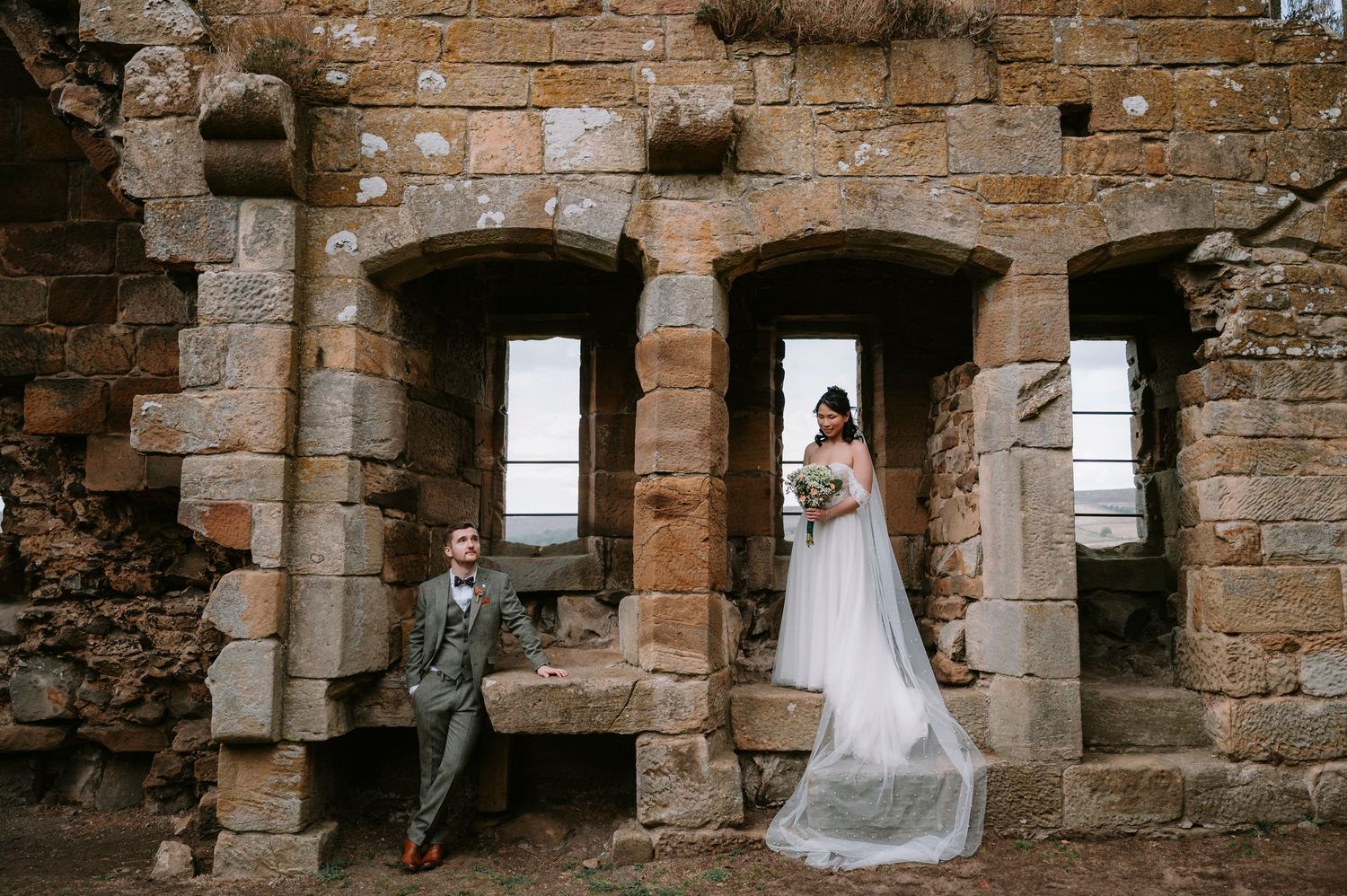 A series of photos showing a bride in a white wedding dress posing against rustic stone walls and window openings.