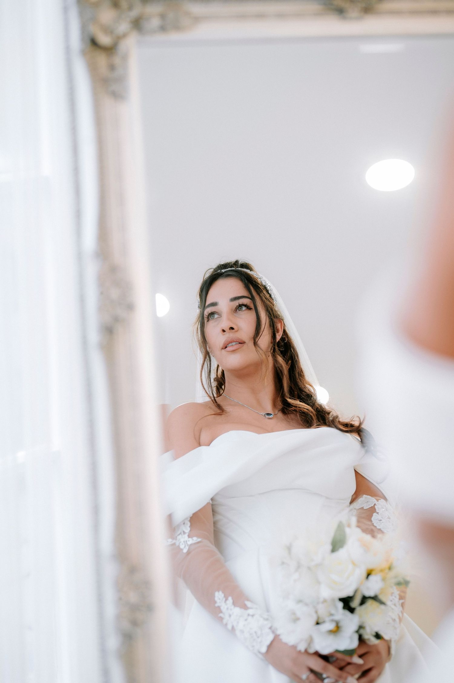 Elegant bridal portrait session with white flowers and ornate mirror frame.