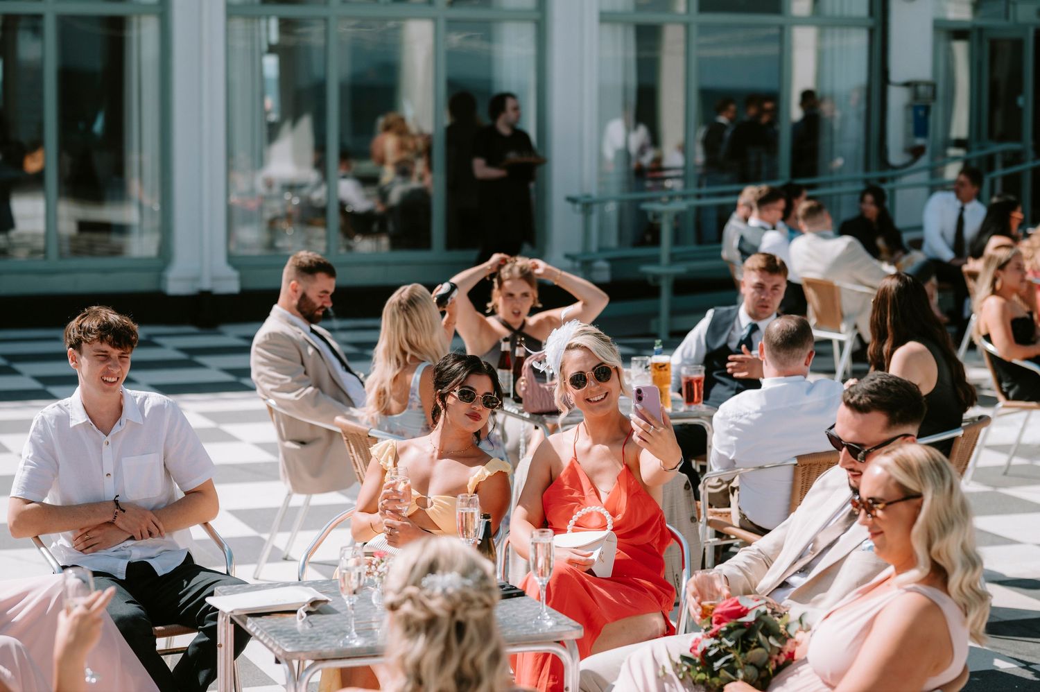 Wedding guests seated outdoors at tables enjoying a sunny celebration.